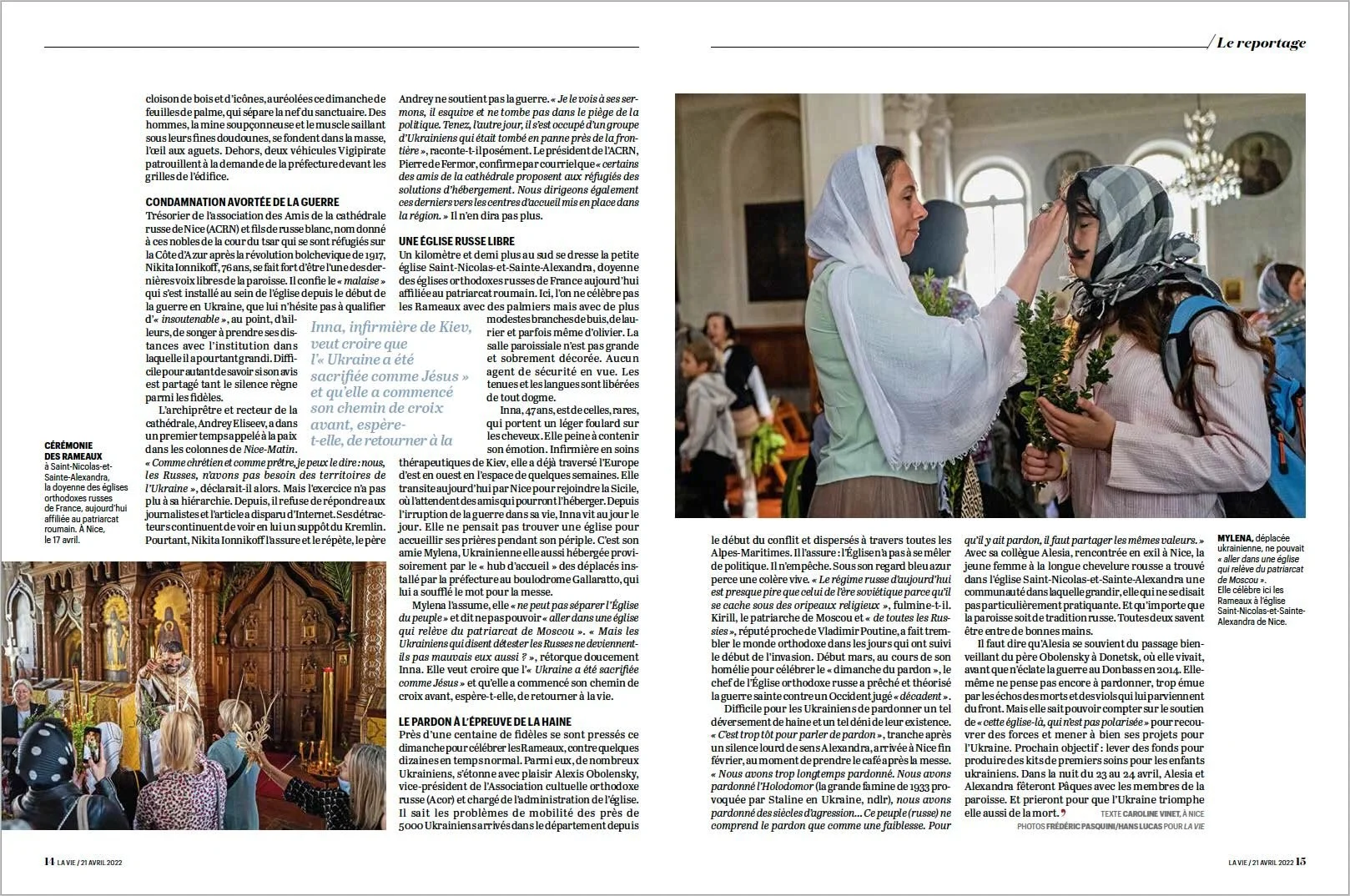 A woman in a white embroidered blouse places a hand on a young girl's head, who is wearing a floral headscarf and backpack, inside a church with a yellow chandelier and visitors.