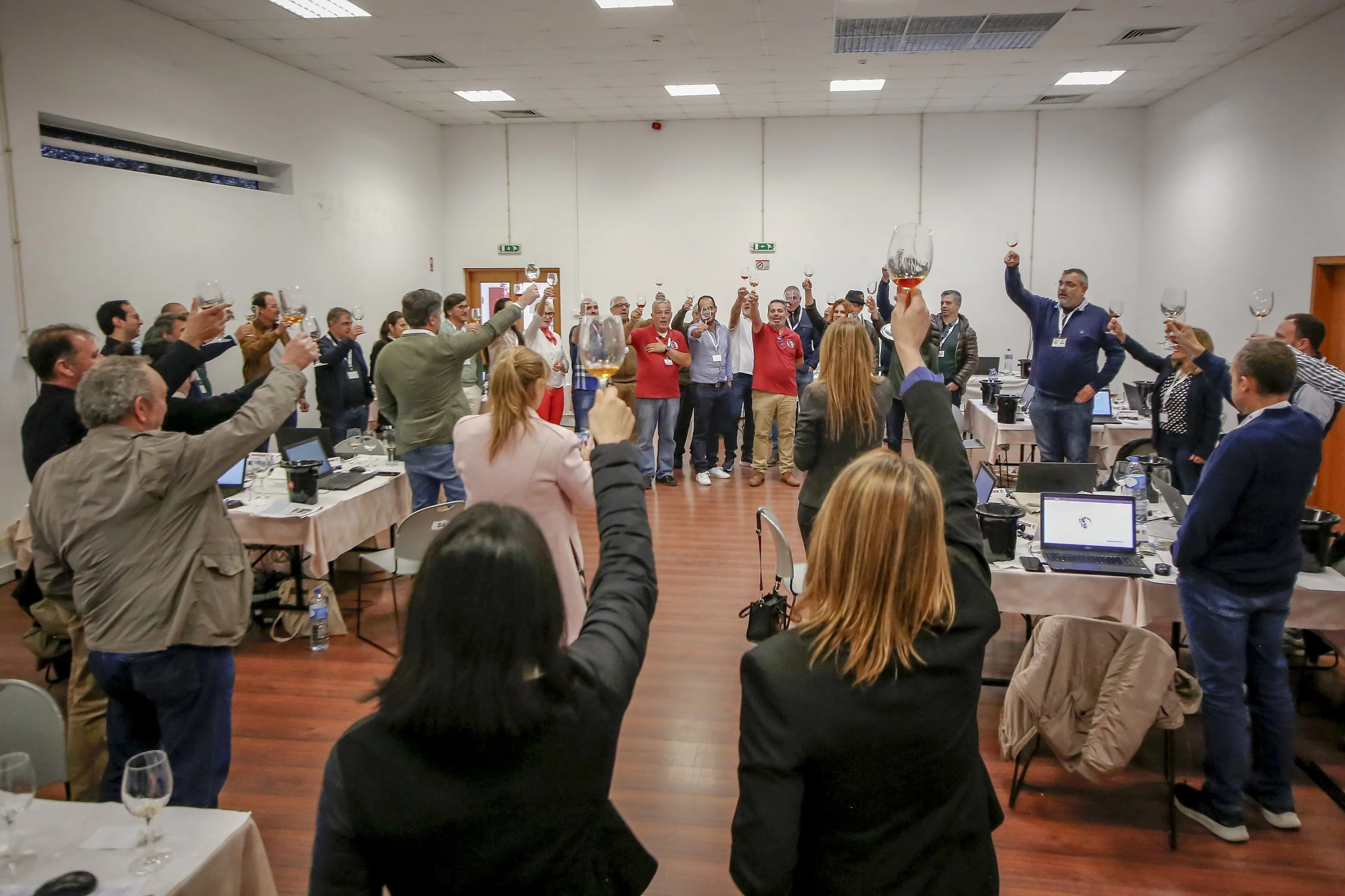 Pessoas em uma reunião de negócios brindando com taças de vinho em um salão de festas.