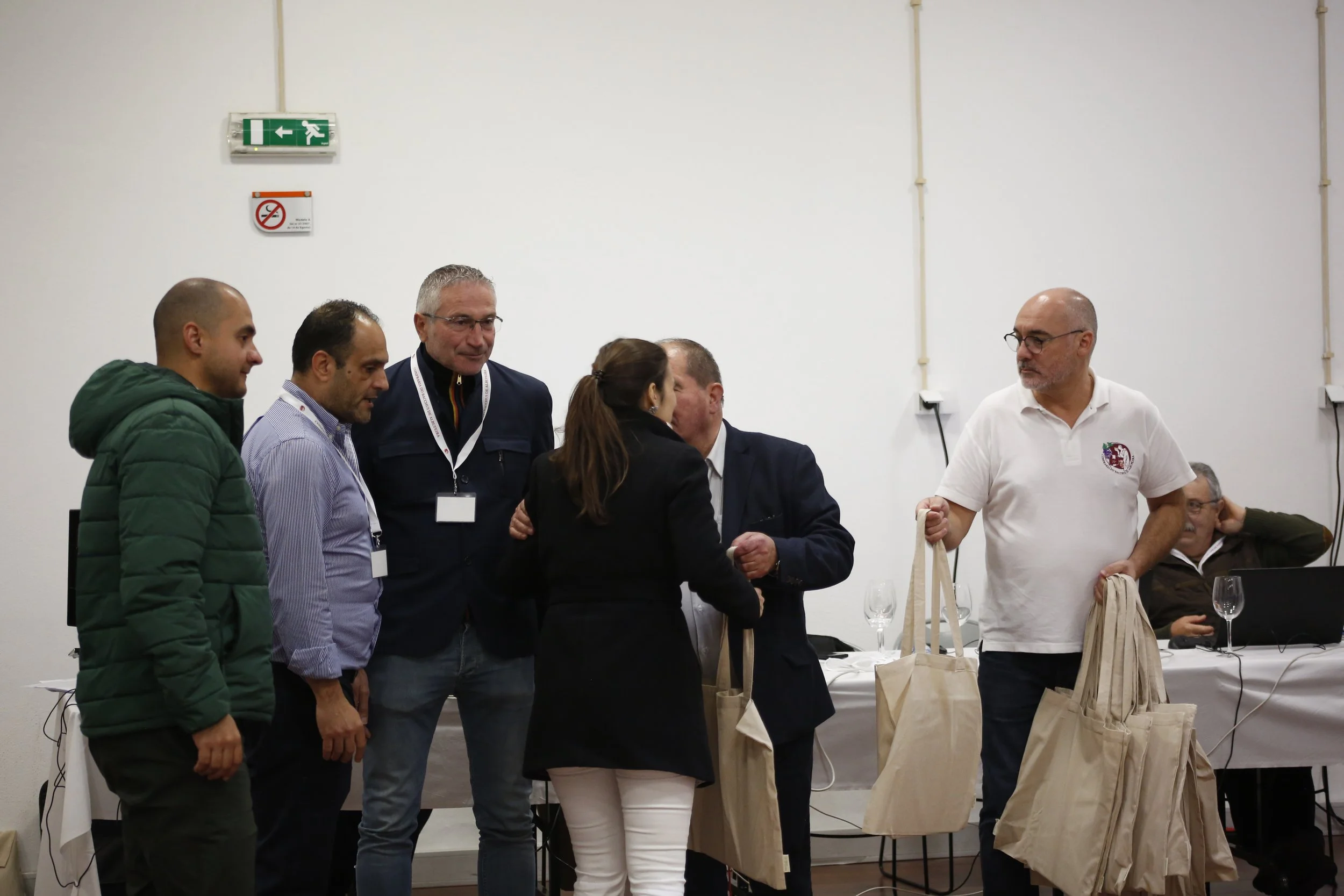 Grupo de pessoas trocando certificados e bolsas em uma sala de reunião