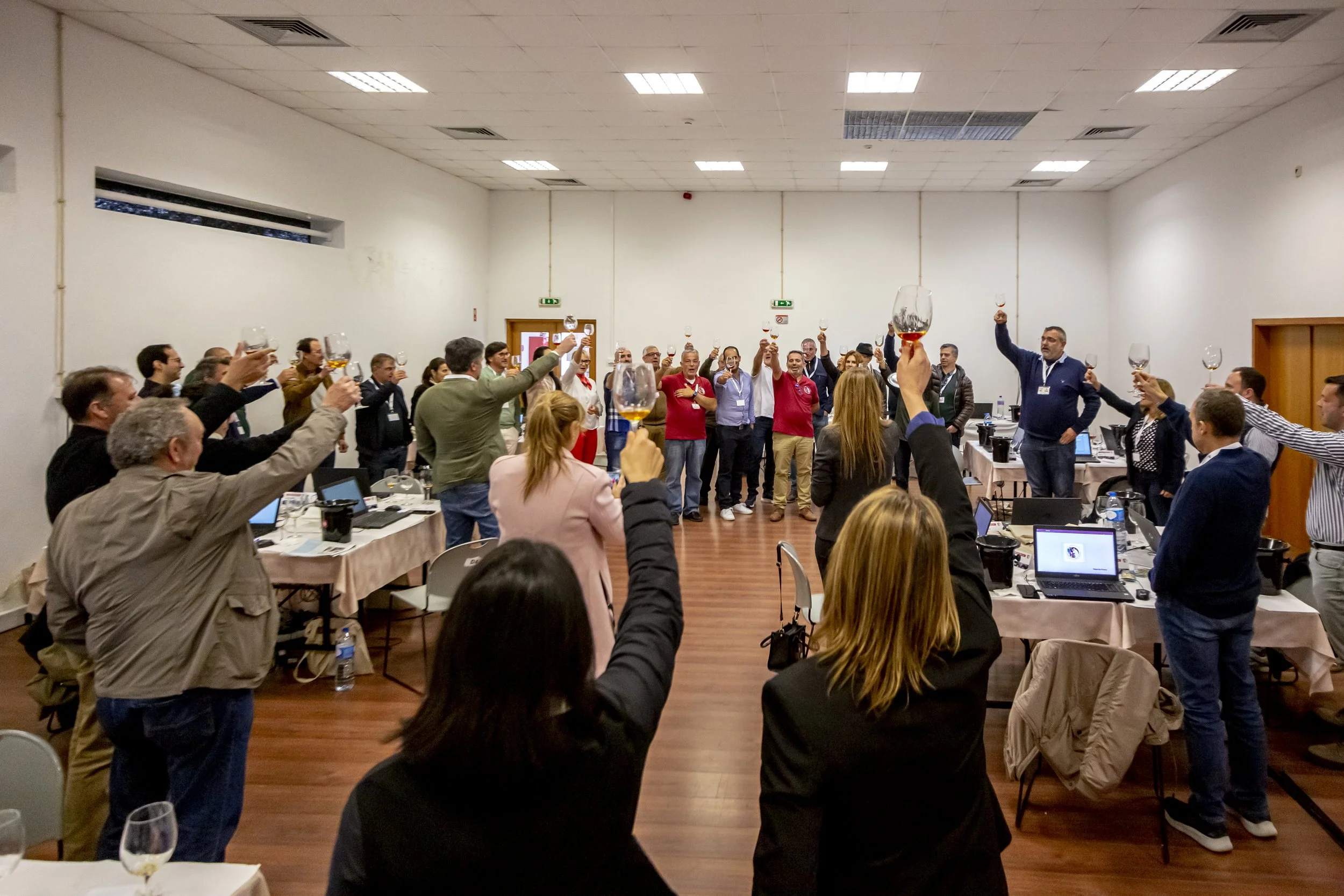 Grupo de pessoas em uma sala de conferências levantando taças em um brinde coletivo.