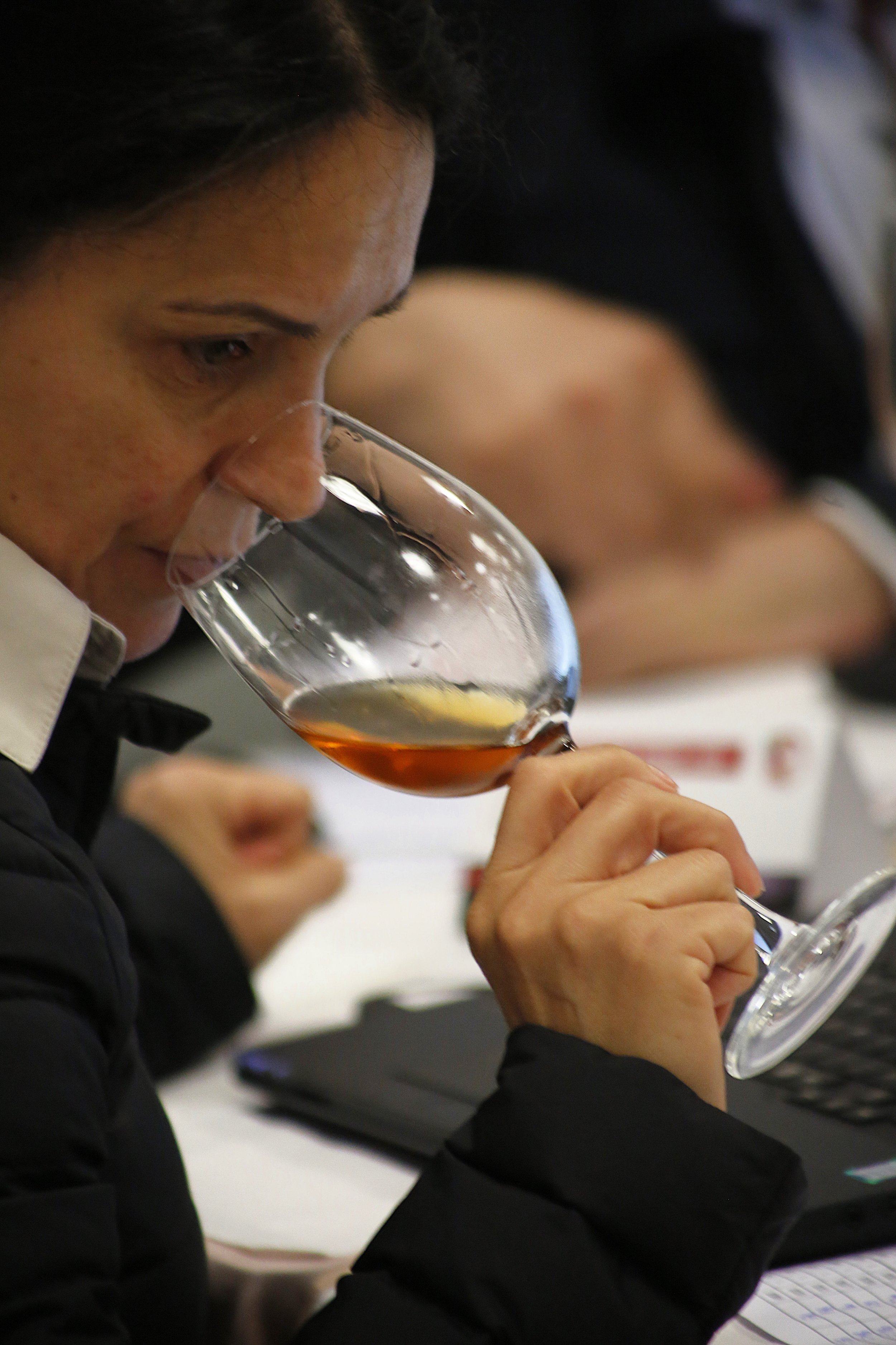 Pessoa degustando vinho em uma taça, com foco na expressão de apreciação.
