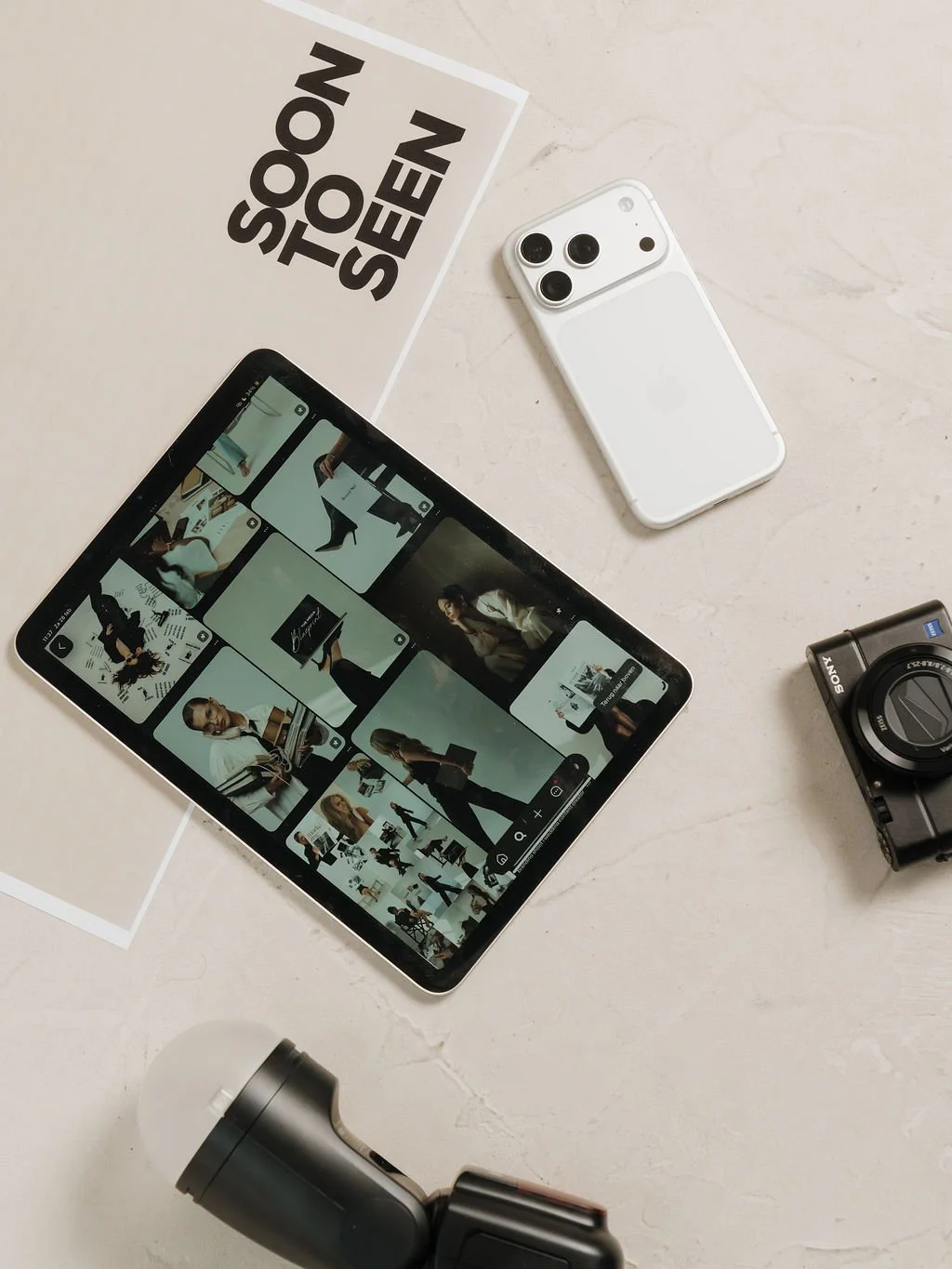 Een tablet, een smartphone, een digitale camera, een projector en een boek op een tafel.