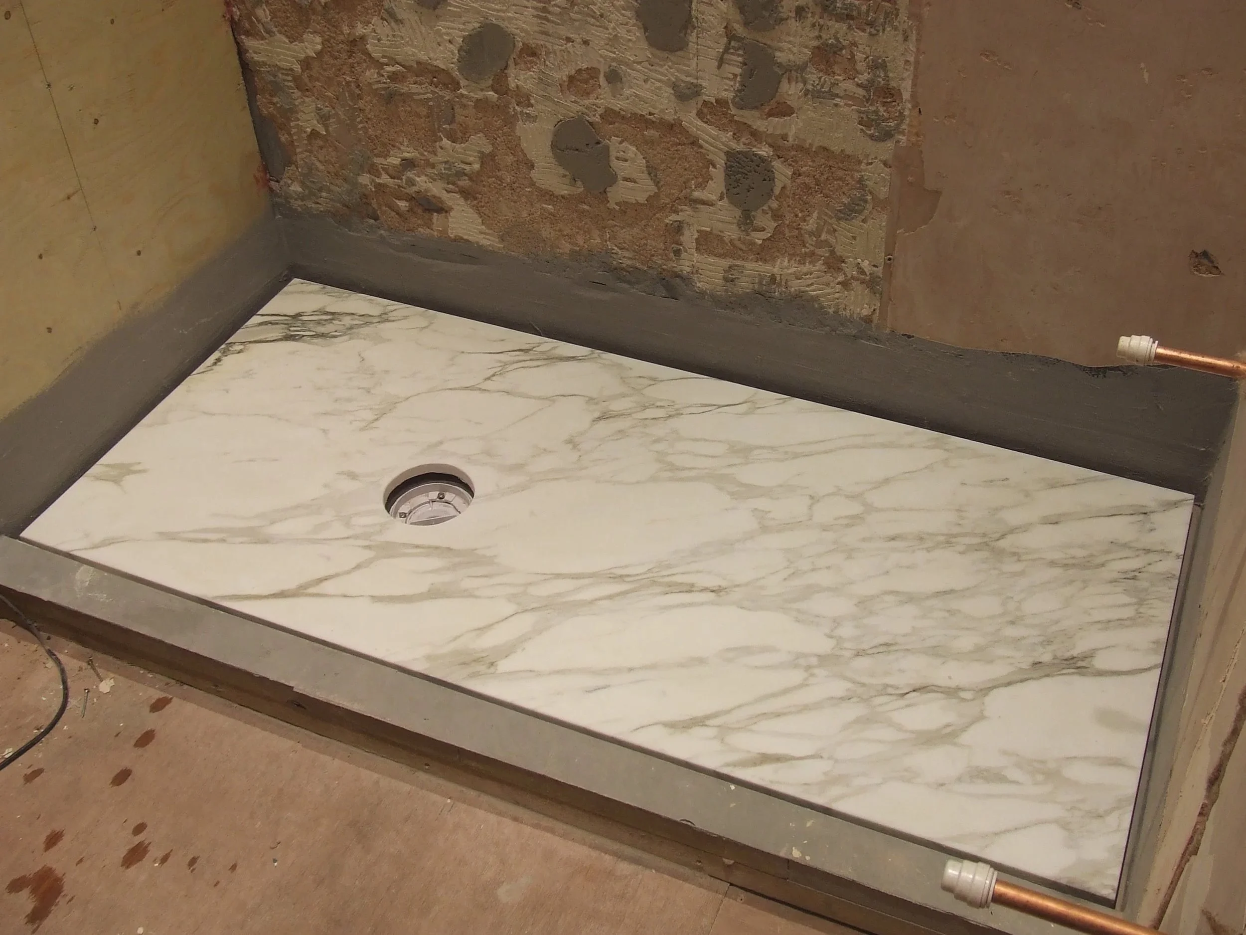 Marble shower tray being installed as part of natural stone bathroom installation