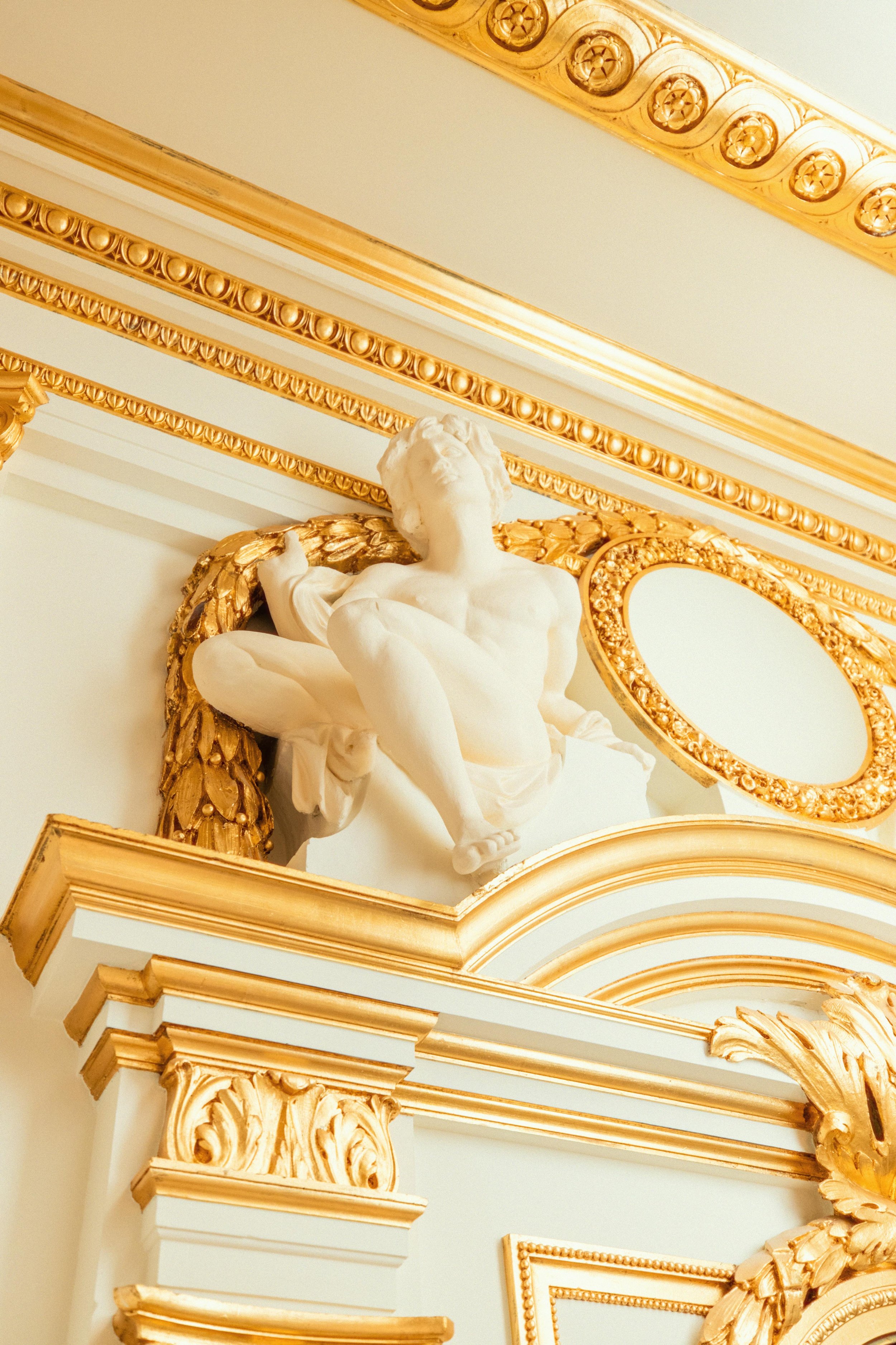 Weiße Skulptur eines geflügelten Jungen als dekoratives Element in einer luxuriösen Zahnarztpraxis mit barocken, goldverzierten Details.