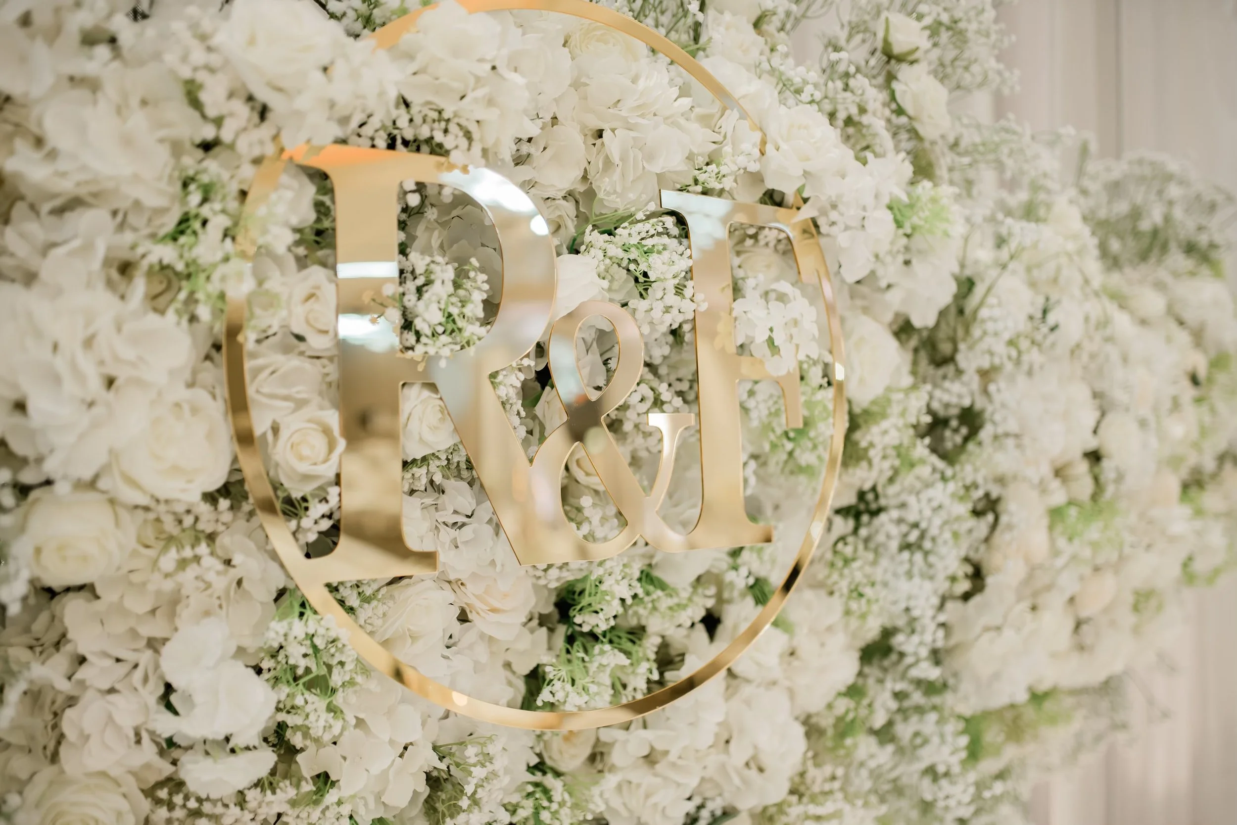 A decorative wall of white flowers with a gold lettering sign that reads 'LOVE' in script style.