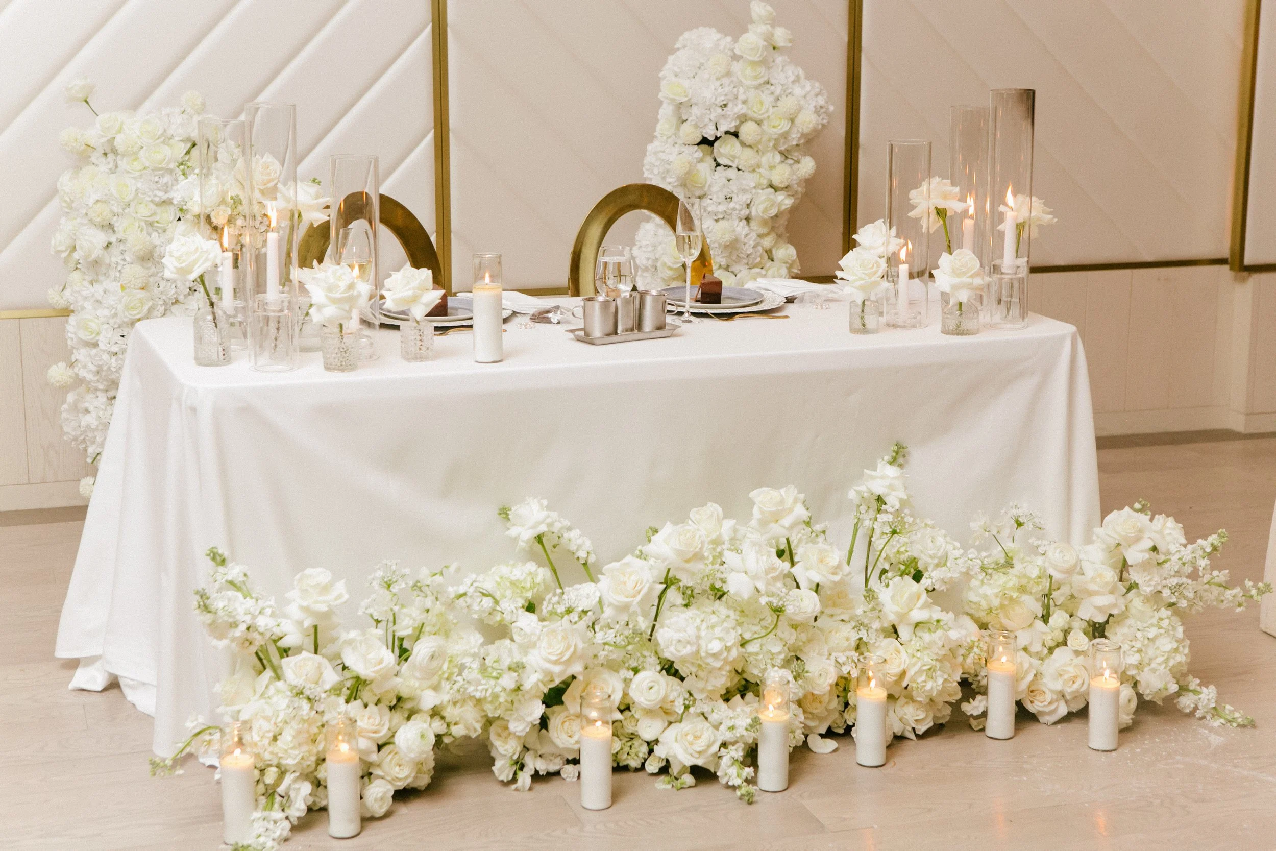 Wedding reception table with white flowers, candles, and place settings