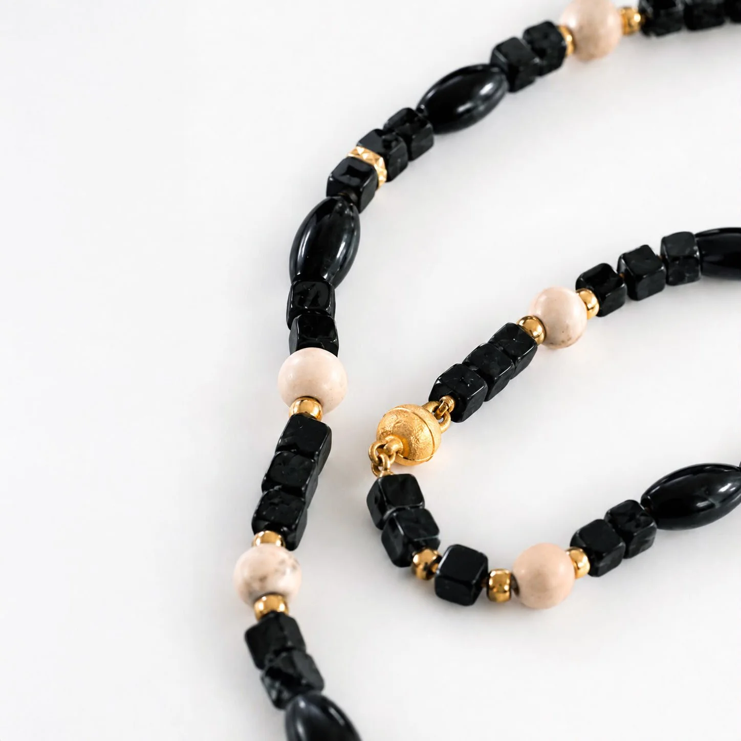 IRISH GRACE : 

Black Kilkenny Marble, Ulster White marble, gold coated 925 silver. Hand-knotted on a silk thread.