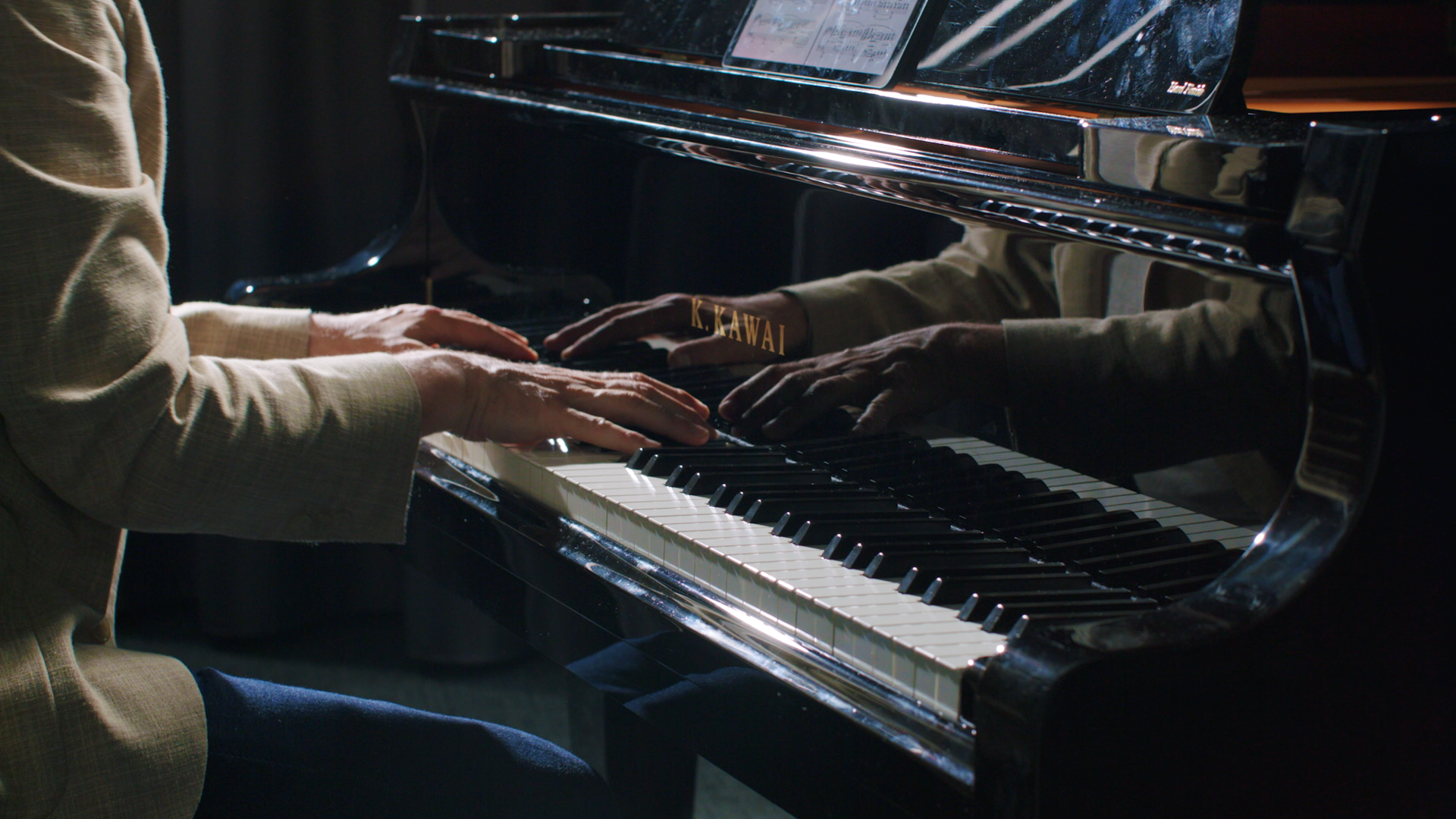 Personne jouant du piano noir à queue avec une réflexion visible sur la surface du piano.
