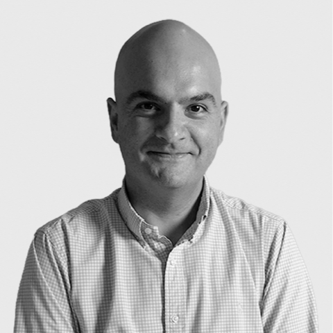 Black and white professional portrait of bald man in suit and white shirt, smiling