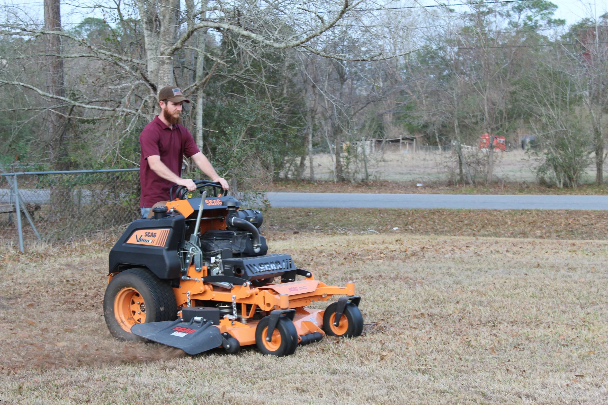 S.I. Lawn Care owner mowing a lawn in Gulfport, Ms with professional landscaping equipment on a grassy yard.
