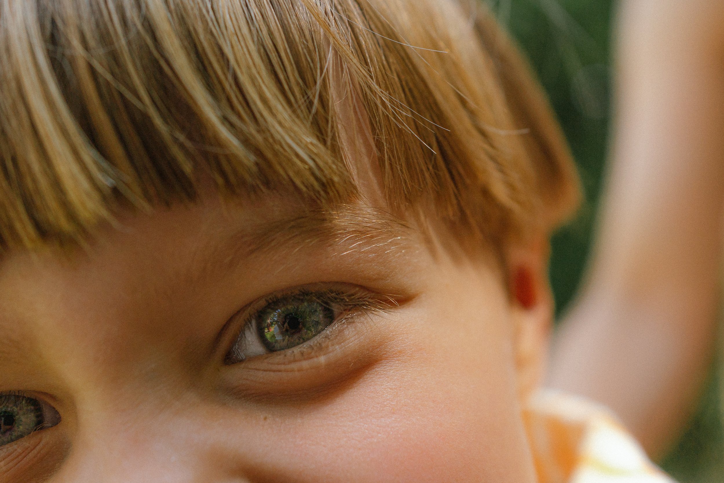 Close-up van een kind met blauwe ogen en blond haar.