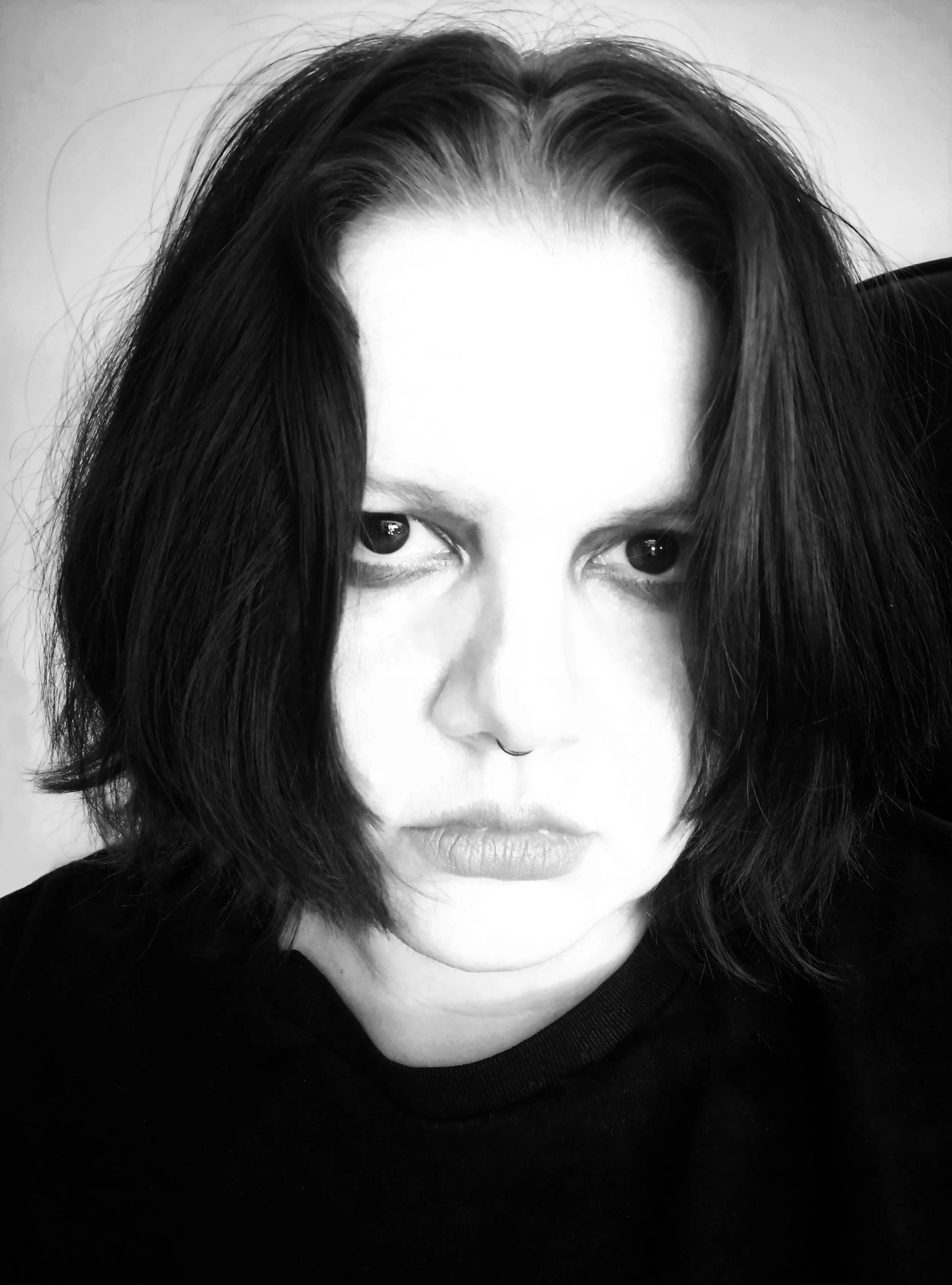 Black and white close-up portrait of a trans man with dark hair and full lips, looking into the camera.