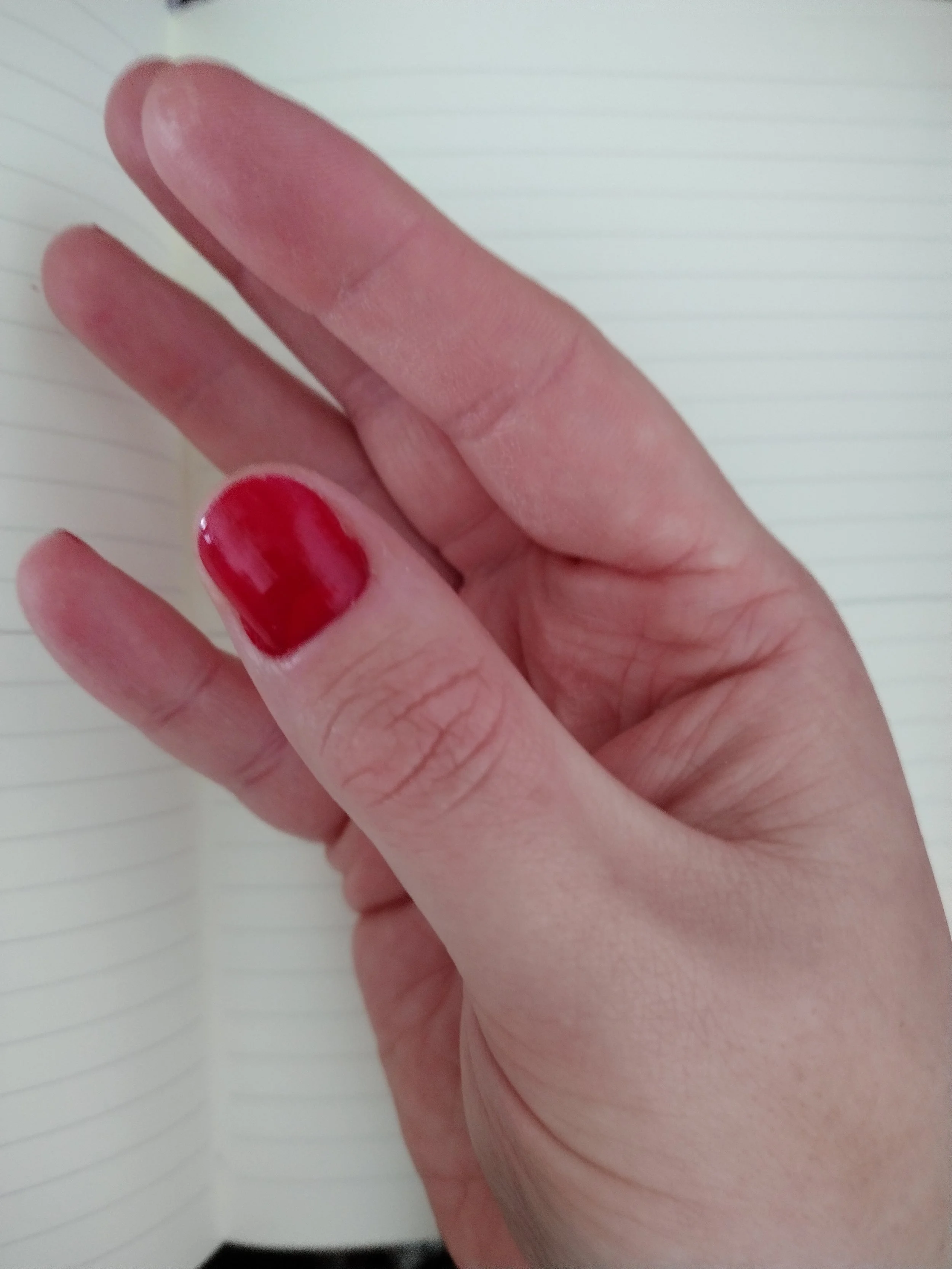 Kaye Outhwaite's hand cramping mid-writing, fingers curled and locked into an unusual position, showing the physical strain of drawing with Dysgraphia.
