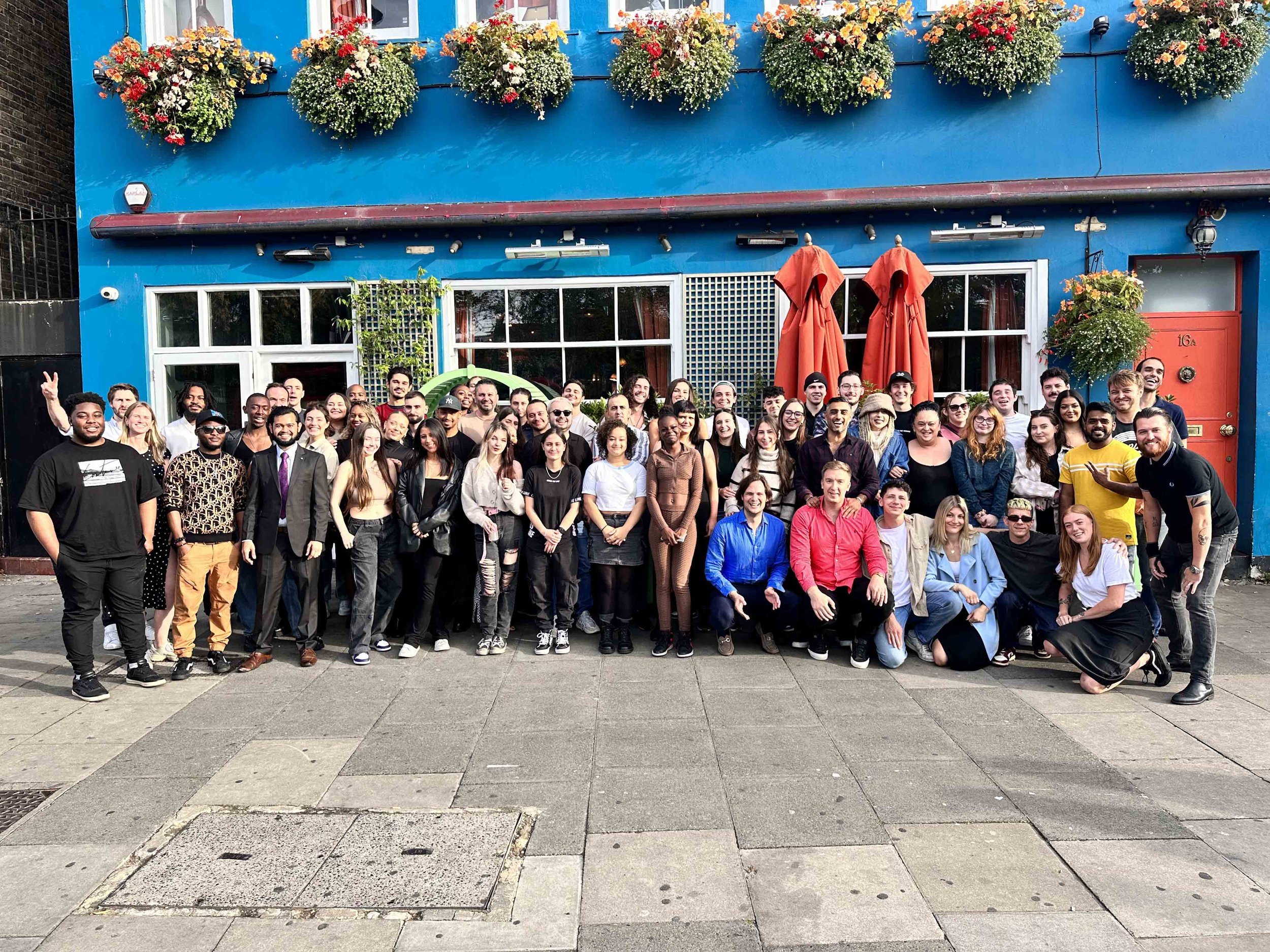 A large group of diverse people posing in front of The Little Orange Door
