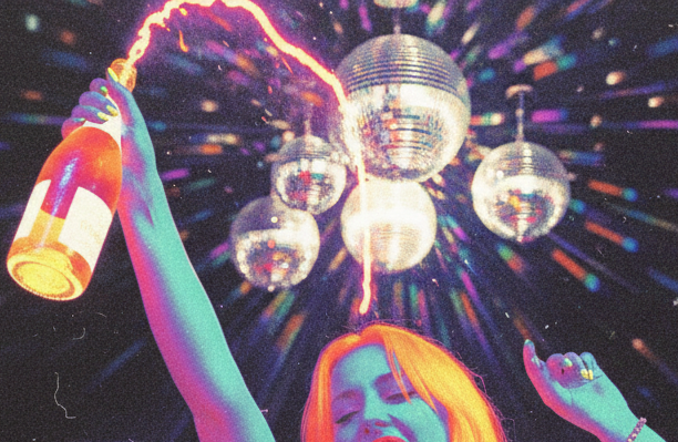 A woman with colorful hair is celebrating with disco balls and a sparkler emitting sparks and light at a party or dance event.