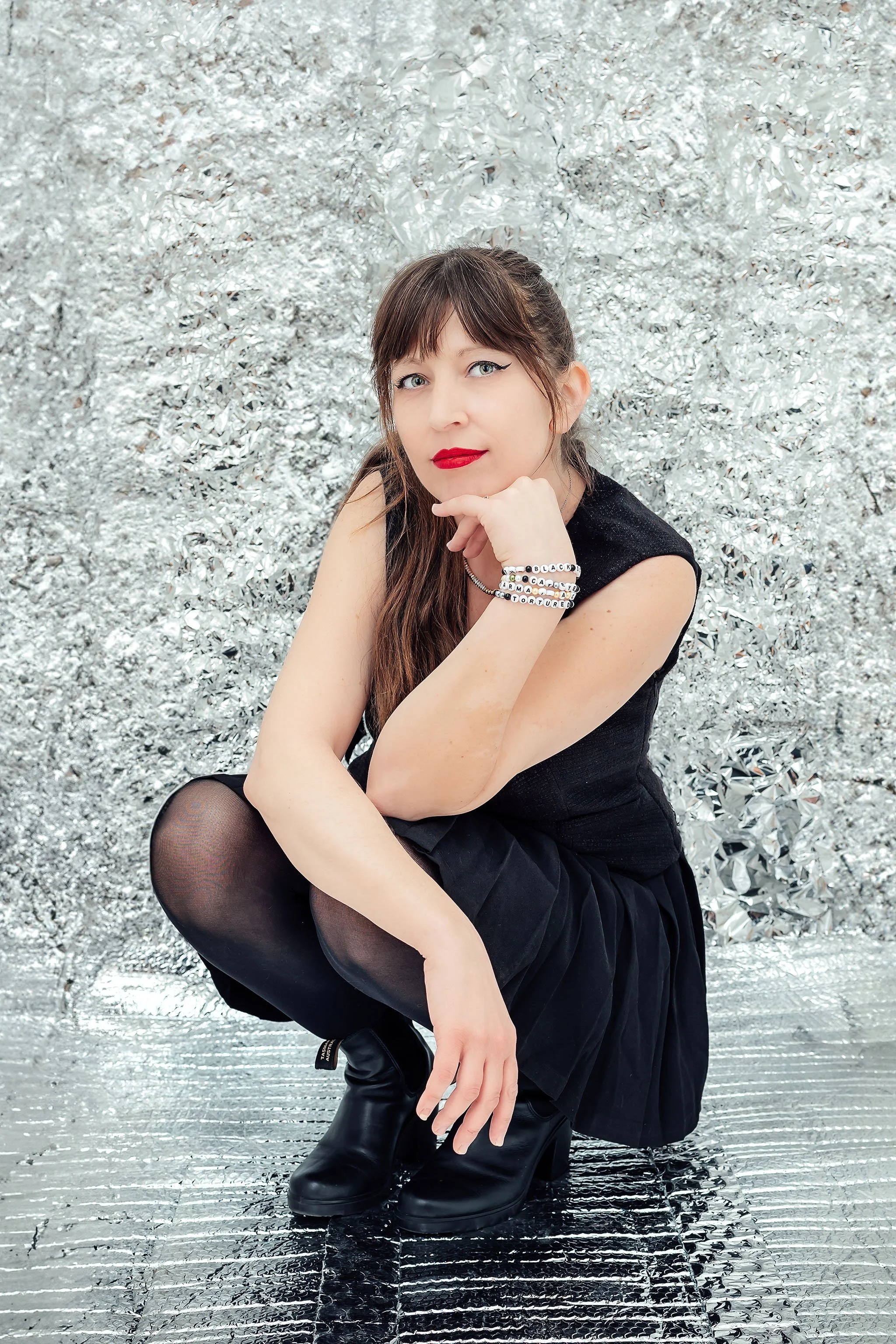Woman in black dress posing surrounded by textured silver walls for editorial portrait