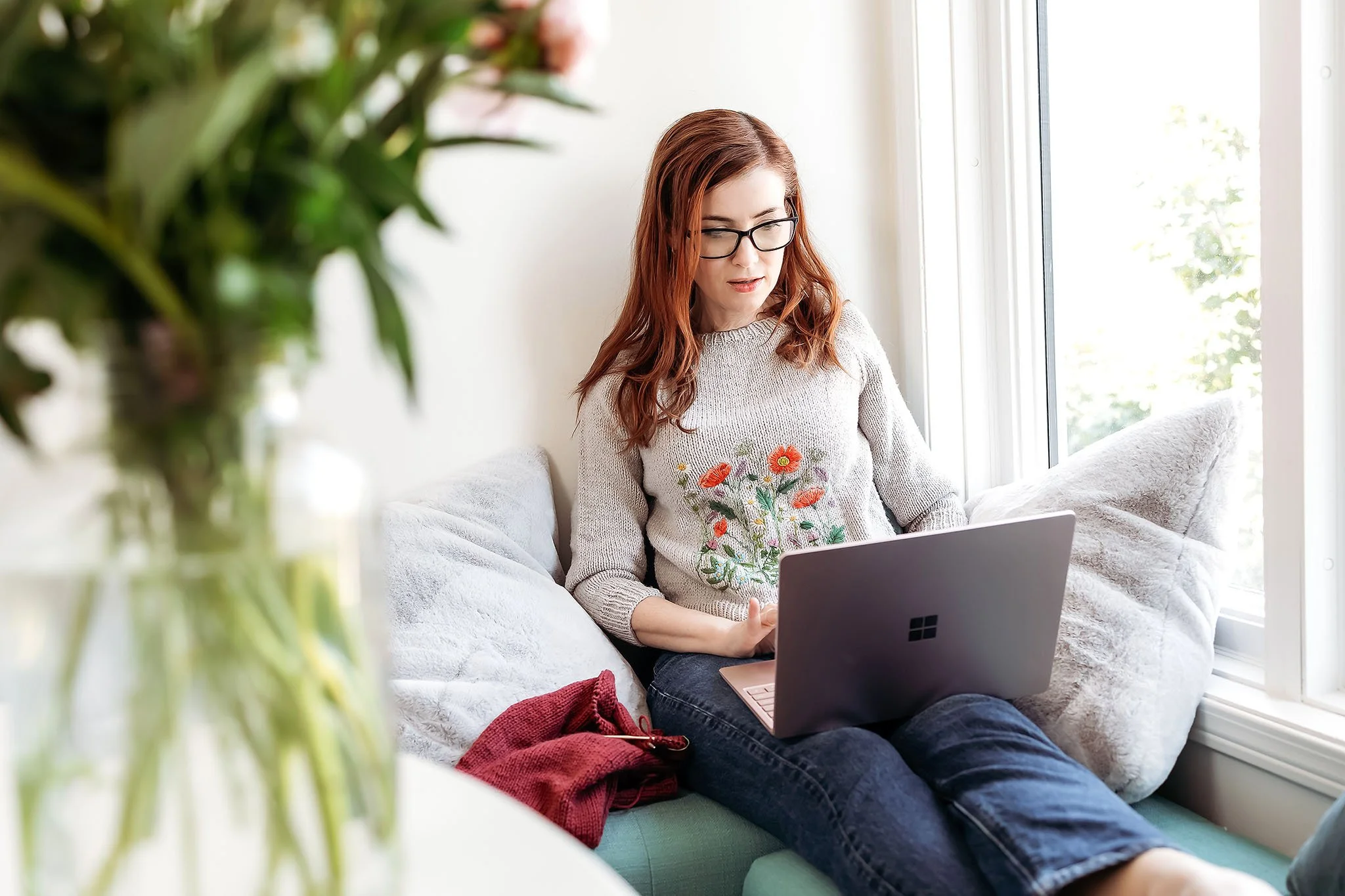 Woman working on laptop near window for personal branding photography session