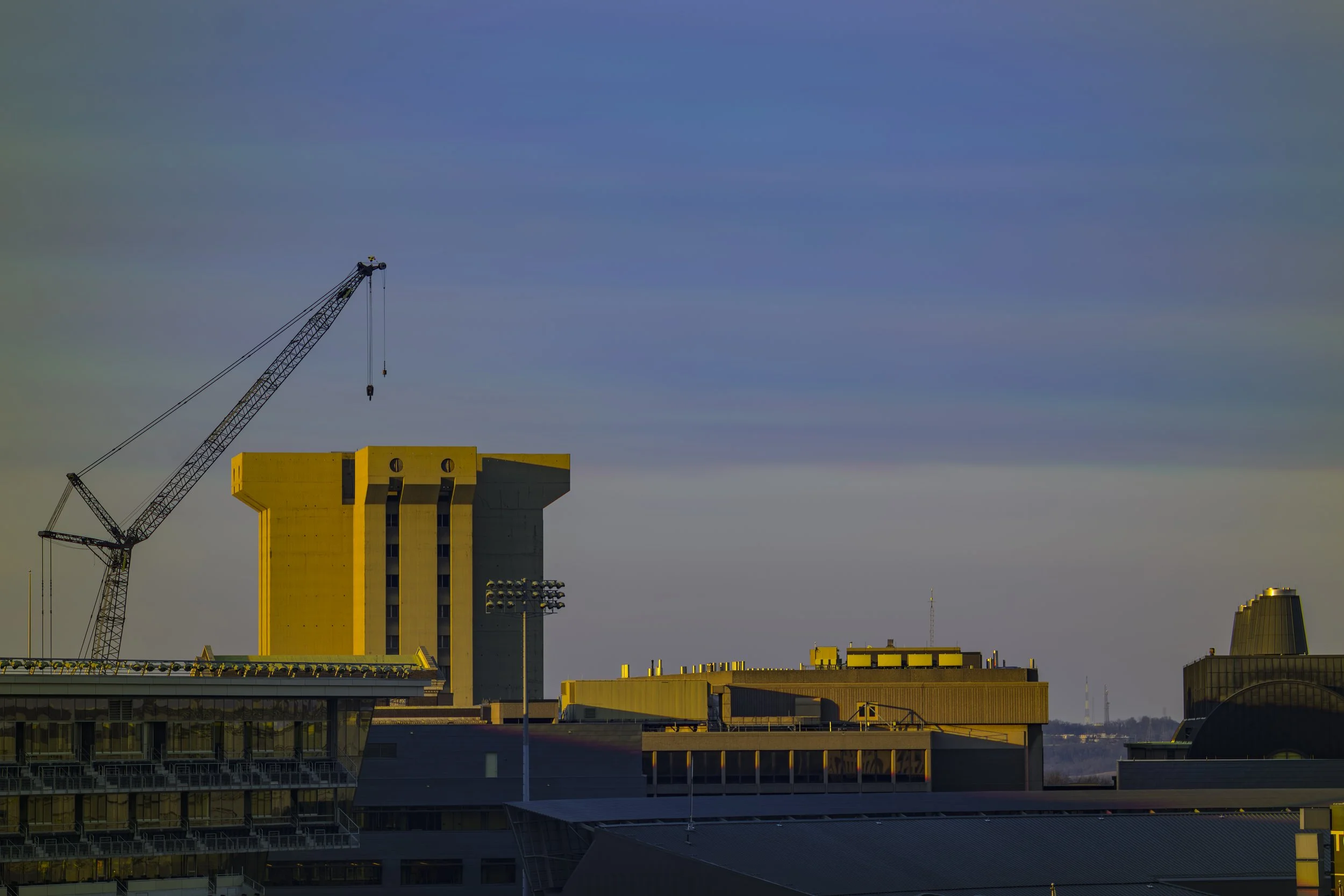 Cityscape featuring a construction crane and buildings under a blue sky with scattered clouds.