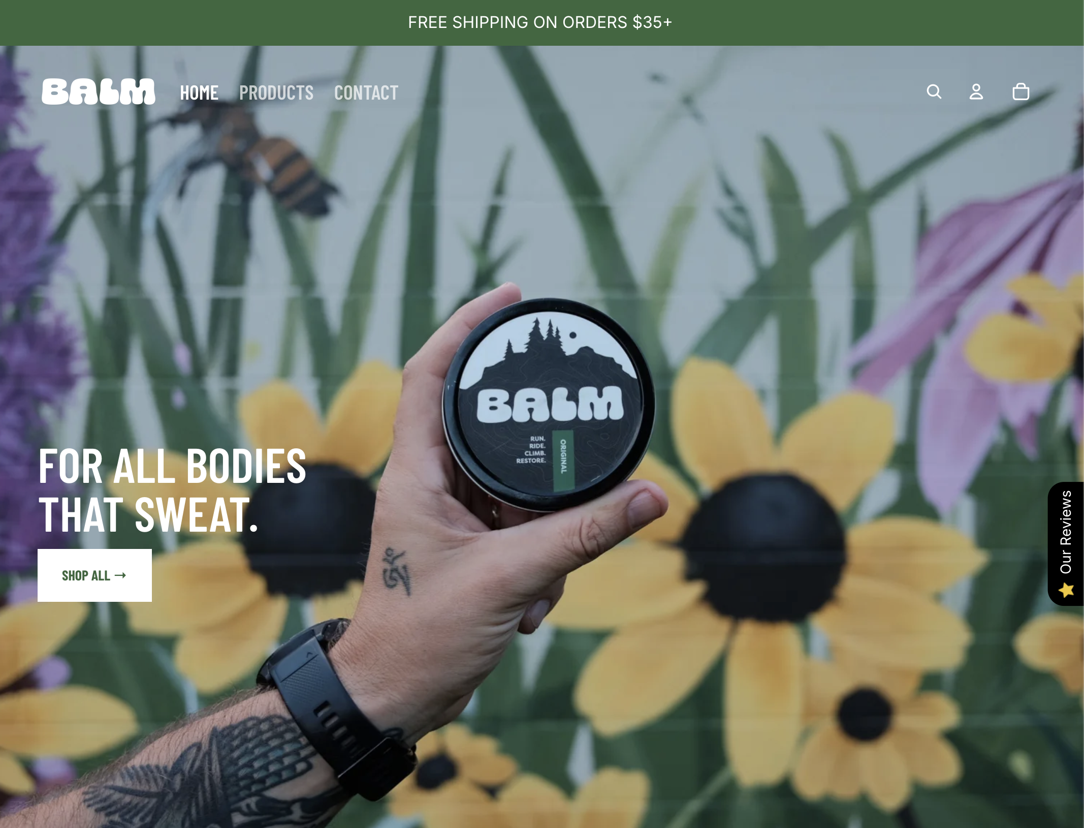 Person holding BÄLM product with a forest and mountain logo in front of a colorful garden wall.