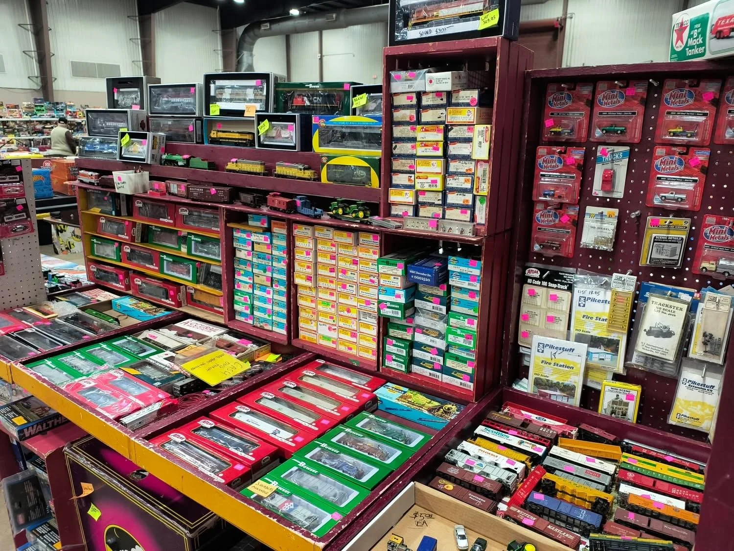 A display of model trains and train accessories at a store, with various boxed models, train cars, and related items arranged on shelves.