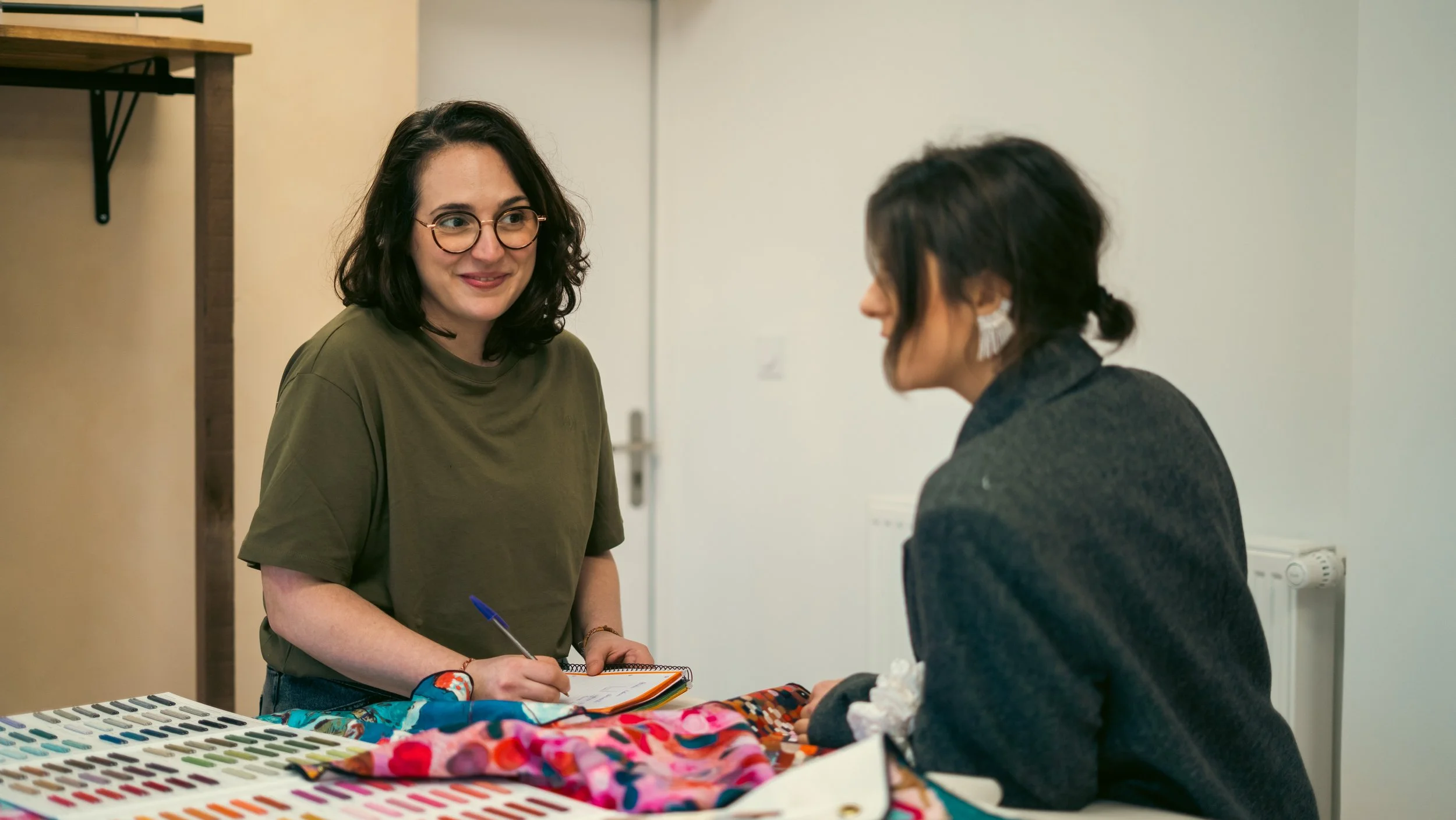 Charline conseille une cliente sur le choix de tissus dans l'atelier CasaMia à Darnétal