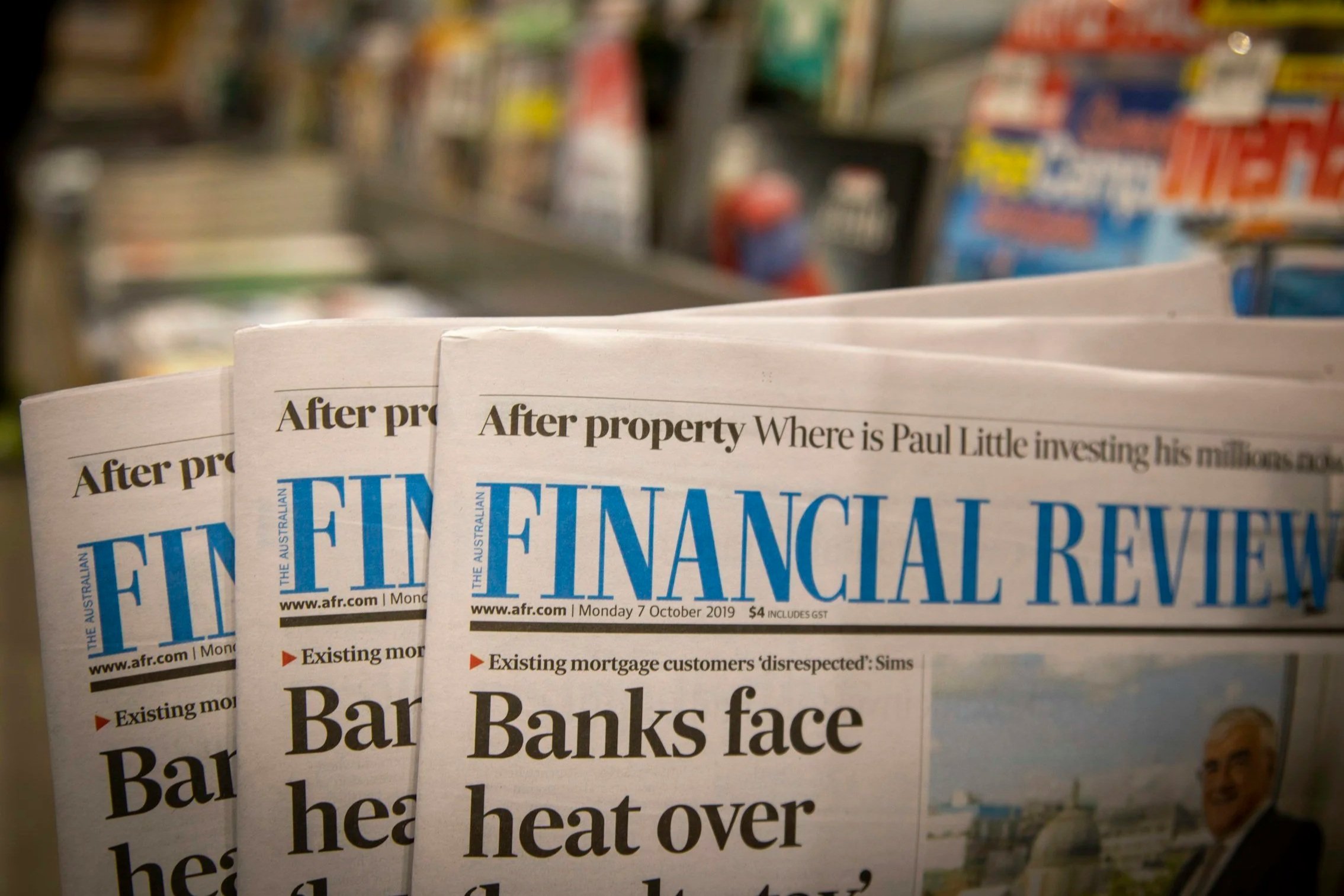 A stack of newspapers on a store shelf, with the headline 'Bar Banks face' visible.
