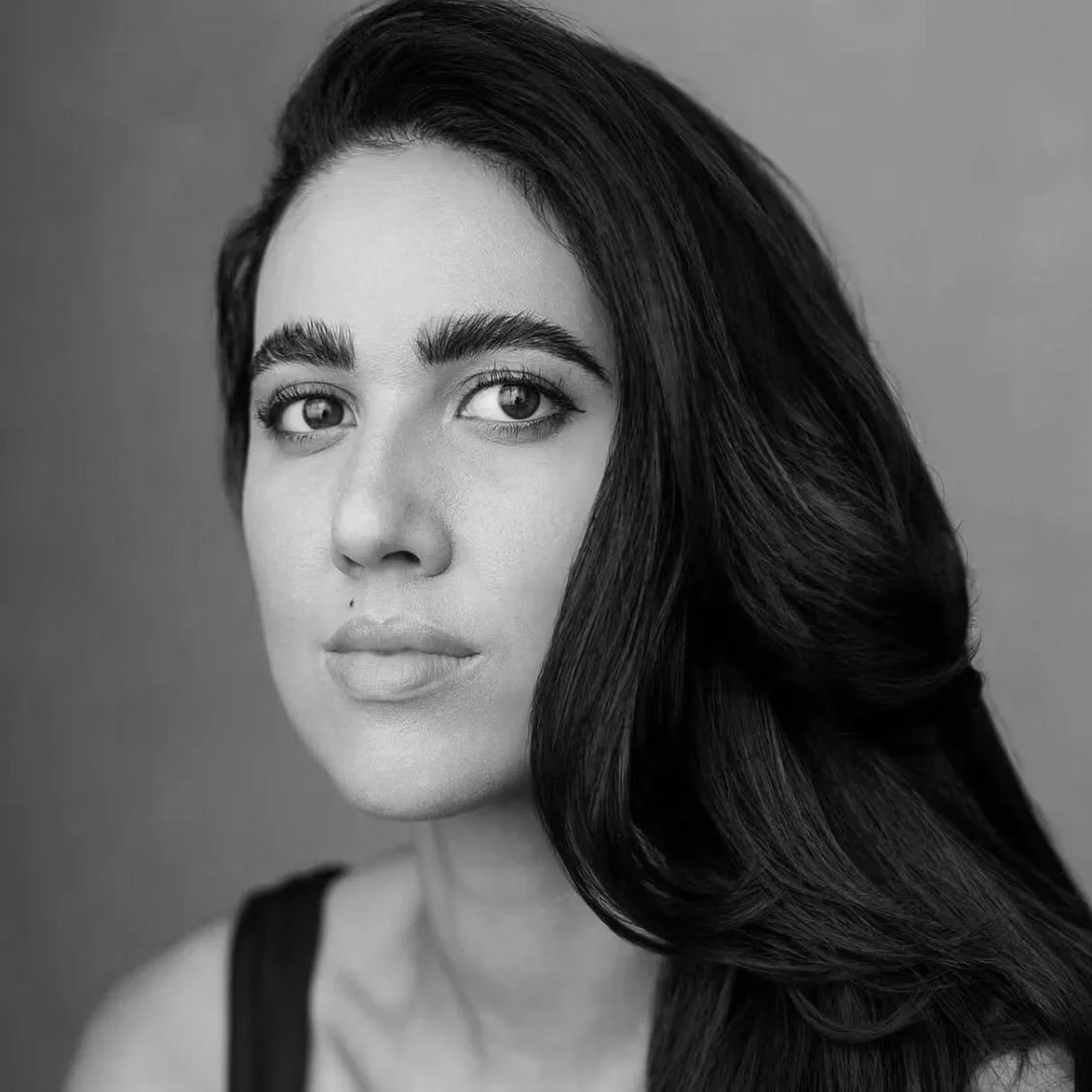 Black and white portrait of a woman with long, dark hair and prominent eyebrows.