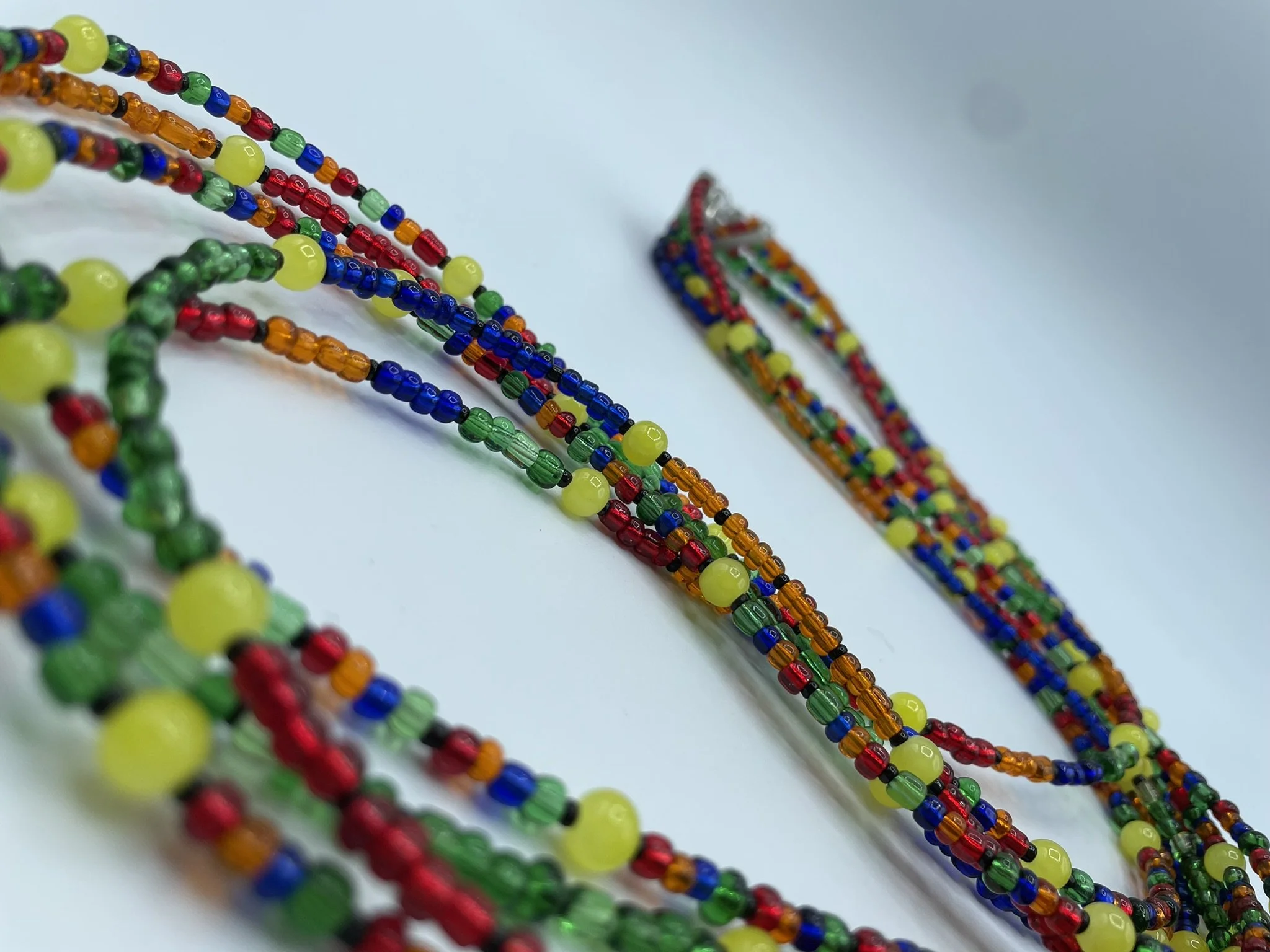 Colorful beaded necklaces laid out on a white surface.