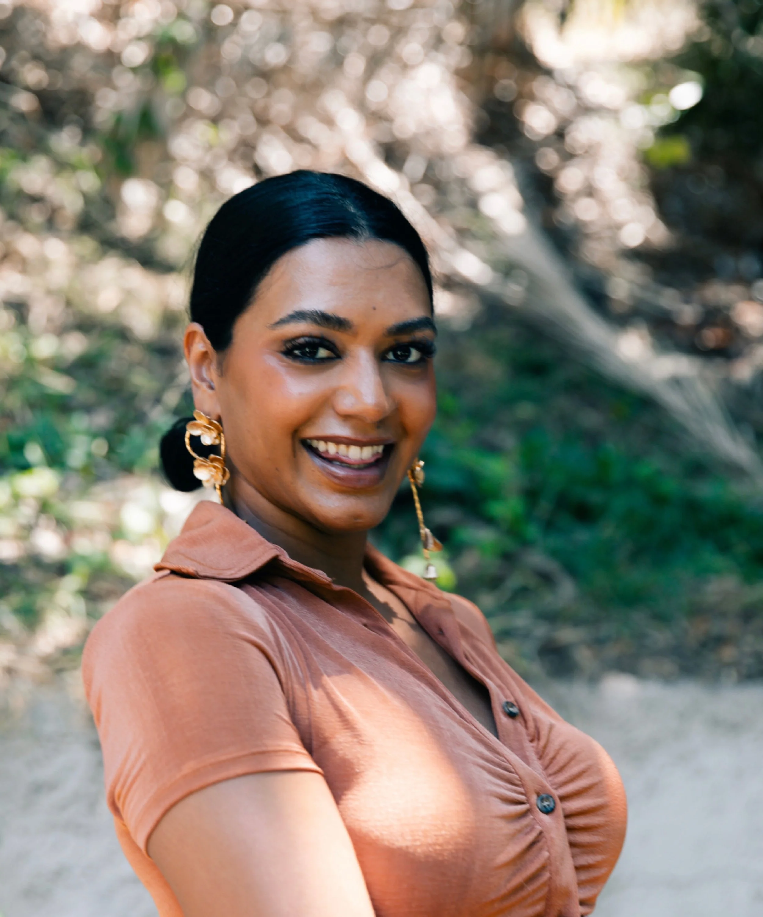 Serita Colette smiling in orange shirt outside in summer time
