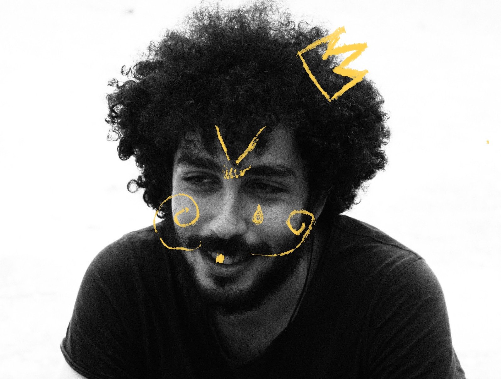 Black and white photo of a man with curly hair, with yellow doodles resembling a mustache, nose, and crowns drawn on his face.