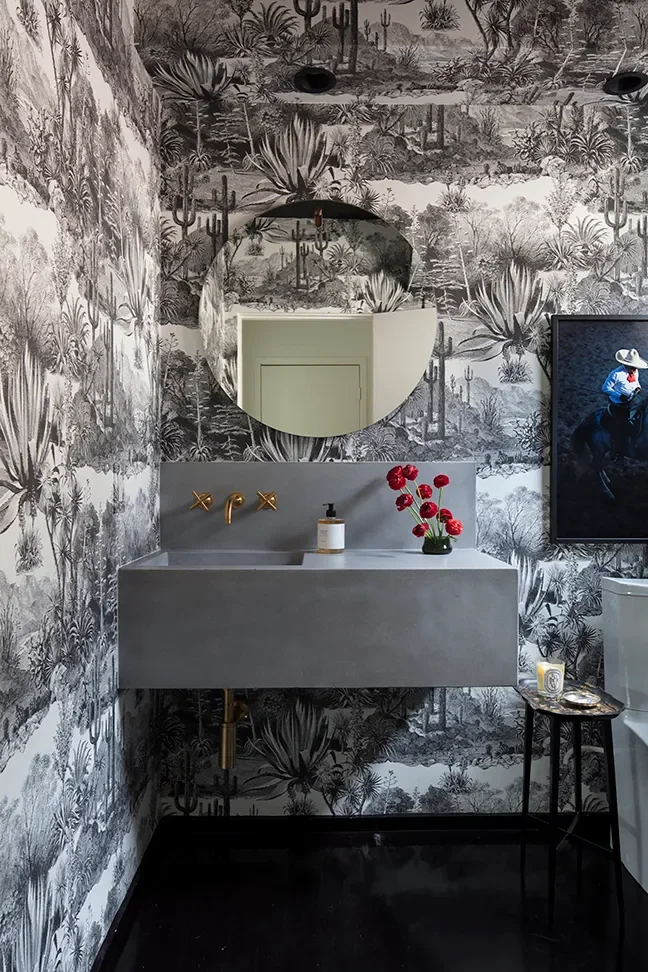 Wrapped in dramatic monochromatic wallpaper, the powder room embraces contrast and refinement. A floating concrete vanity and warm brass fixtures introduce modern restraint, allowing material and pattern to speak with quiet confidence.