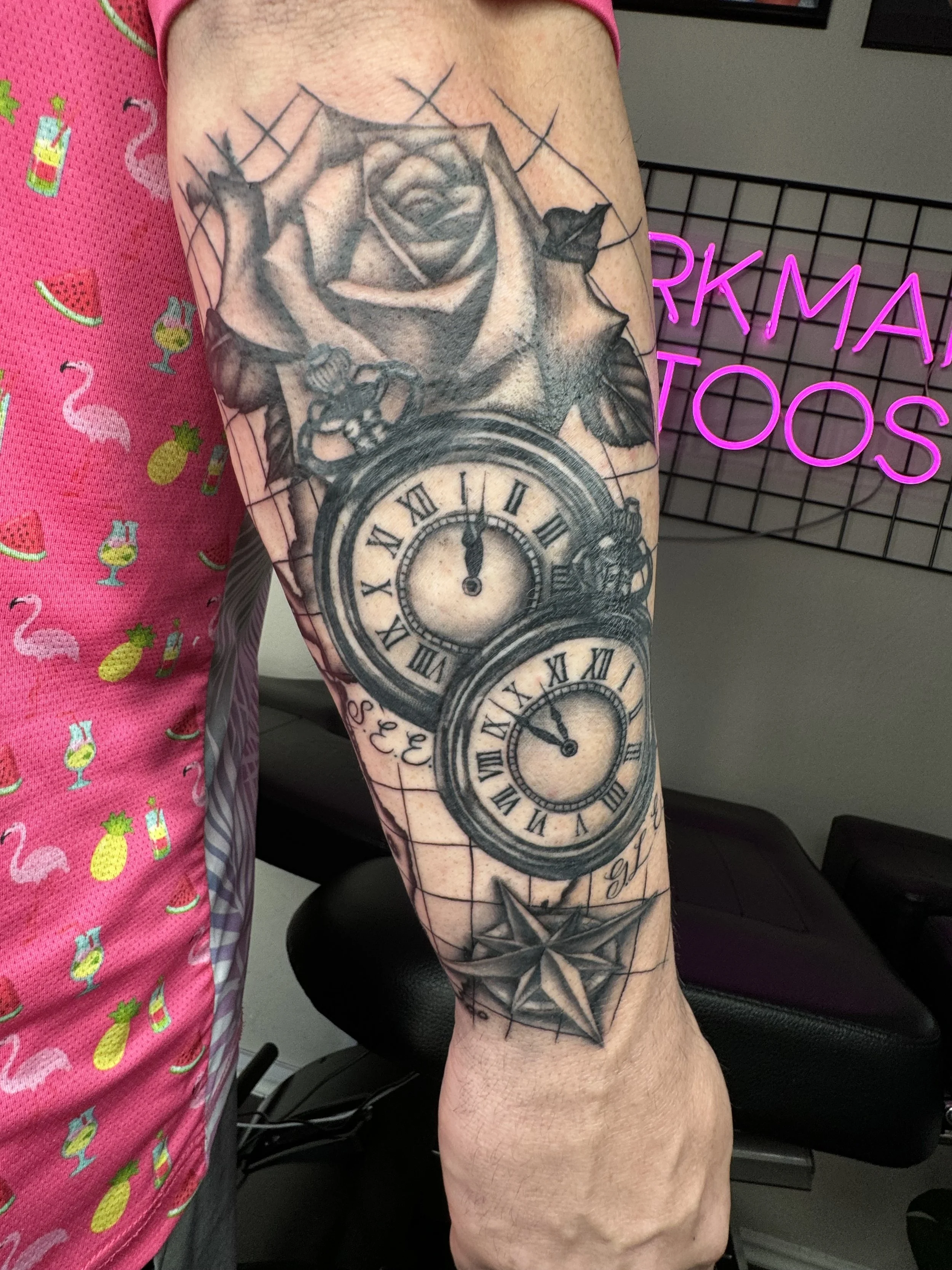 Tattoo of two pocket watches, a rose, a compass, and a star on a person's arm.