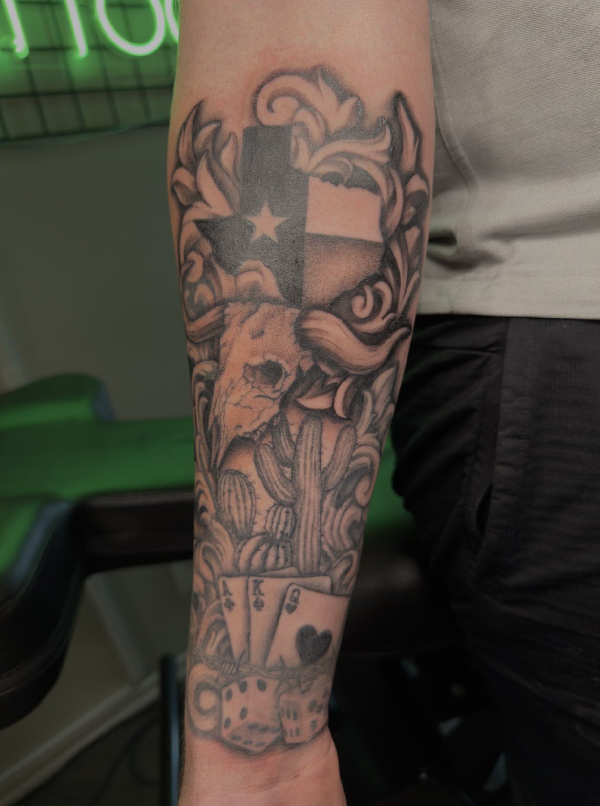 Tattoo sleeve featuring the Texas flag, a skull, cacti, playing cards, and dice.