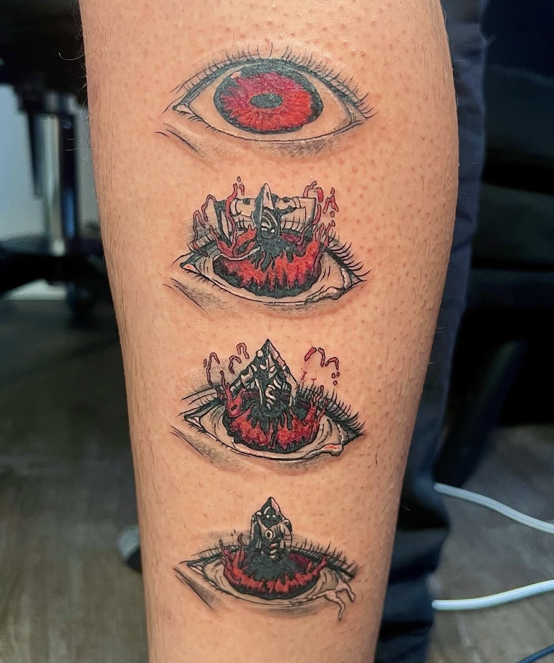 Tattoo of four eye illustrations in a vertical line, each with red and black color themes.