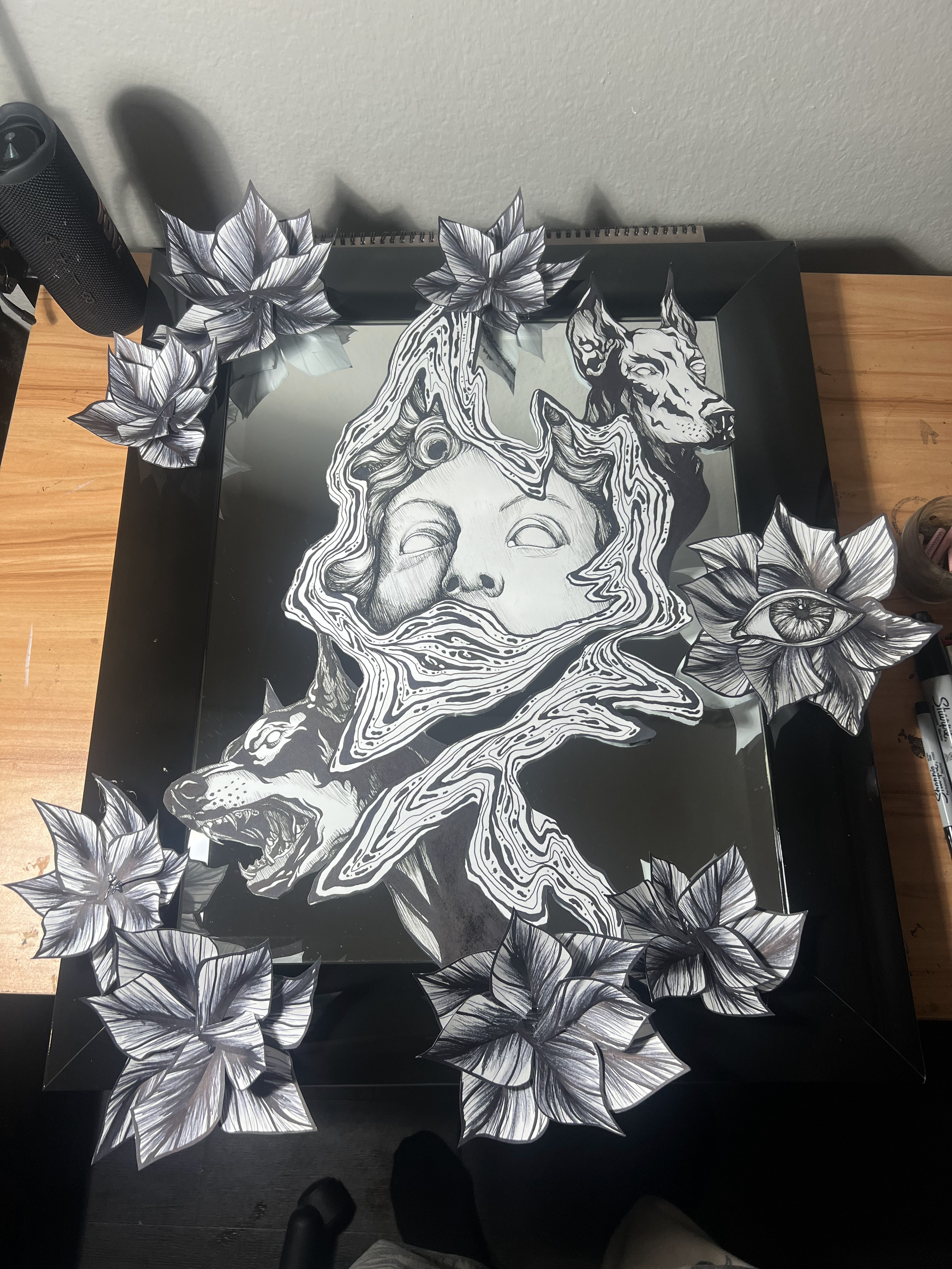 Black and white artwork features a child's face with closed eyes, surrounded by swirling patterns, a wolf, a dog, an eye, and various floral elements, all in a dark shadow box frame.