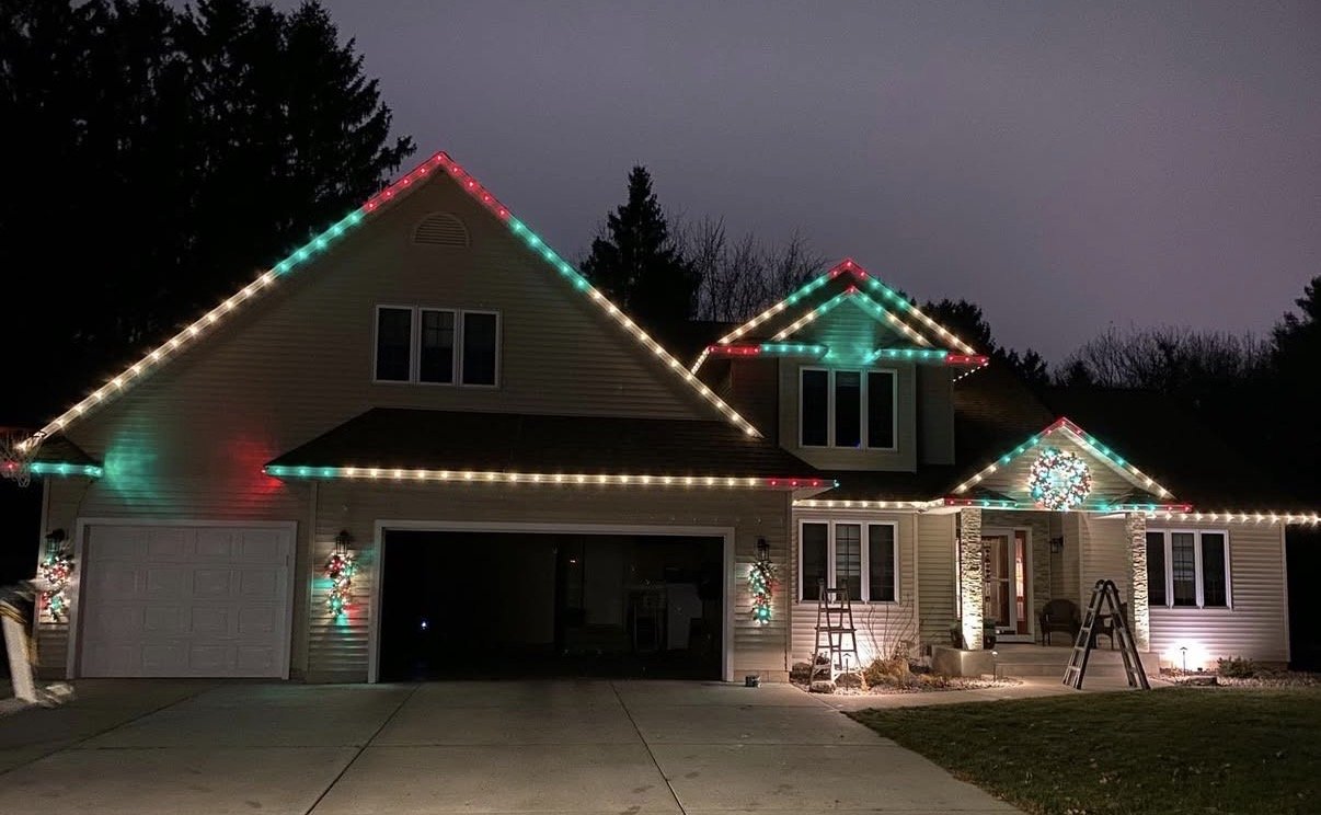 A house decorated with colorful Christmas lights and a wreath on the front door during the evening.