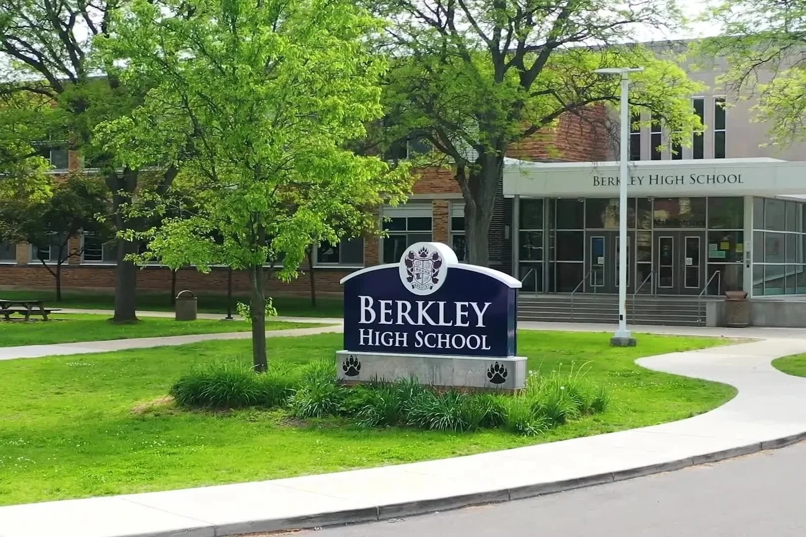 Sign reading 'Berkley High School' in front of a school building with trees and a sidewalk.