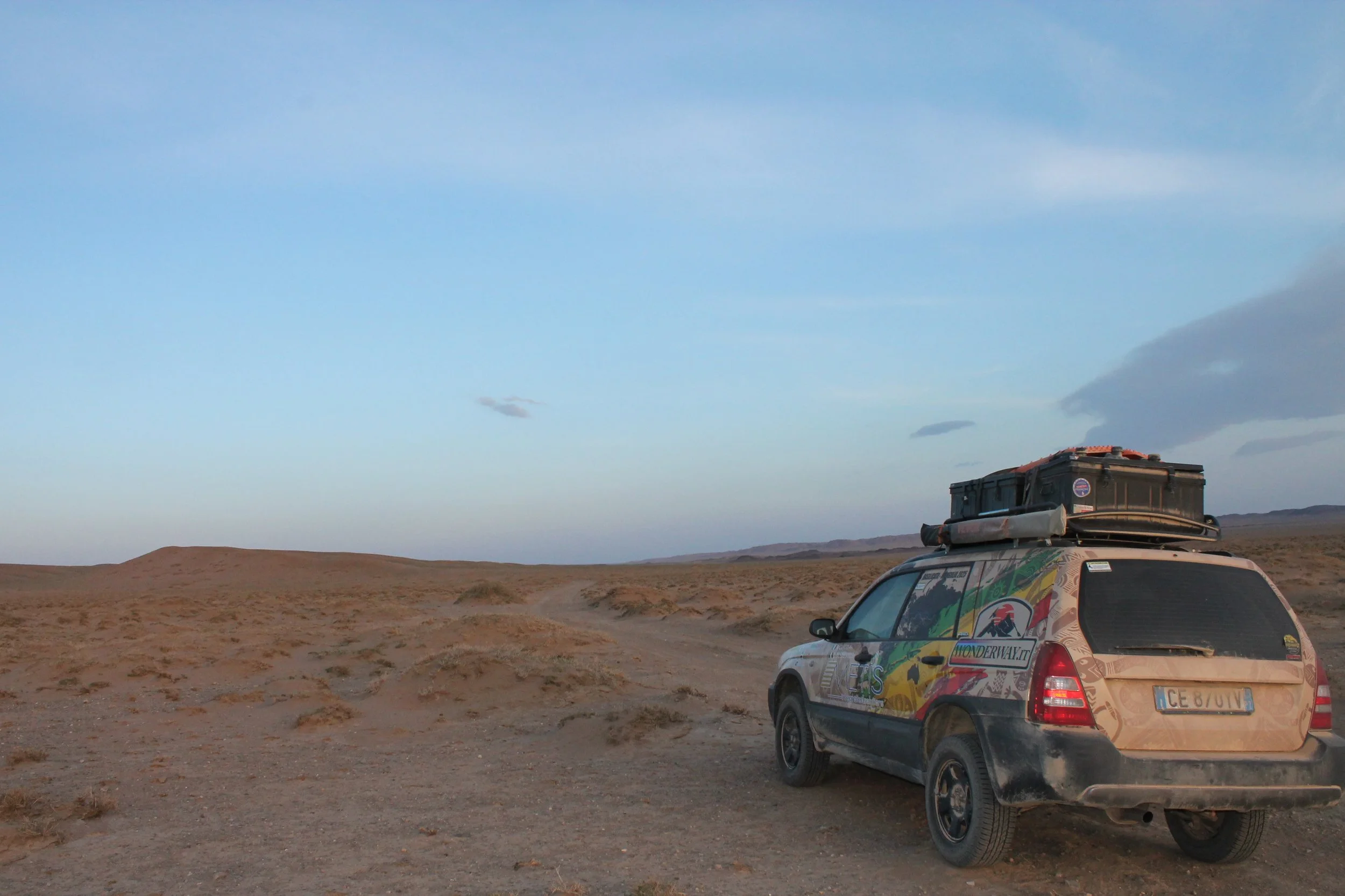 Auto deportivo con maleta sul tetto in un paesaggio desertico