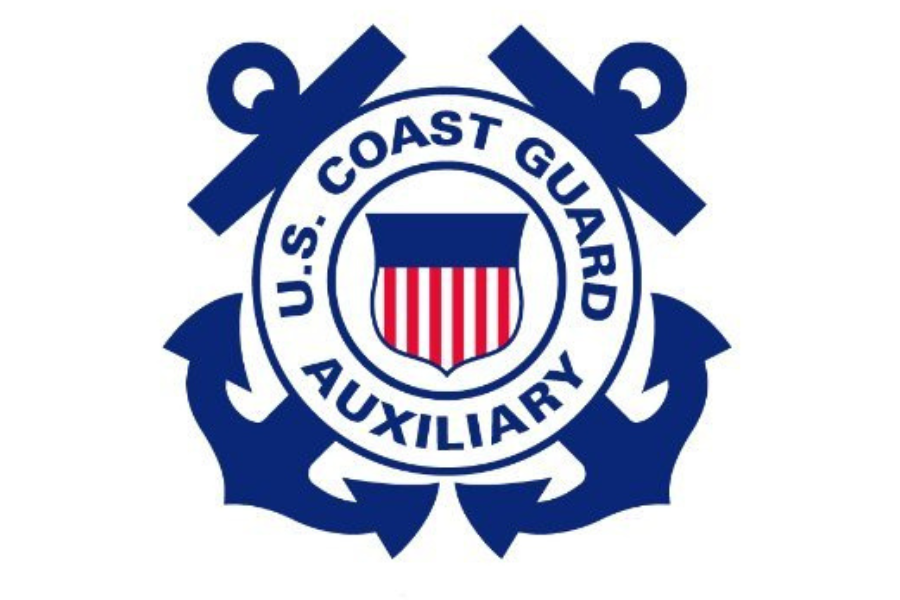U.S. Coast Guard Auxiliary emblem featuring a circular design with navy blue anchors, a shield with red and white stripes, and the words "U.S. Coast Guard Auxiliary" around the circle.