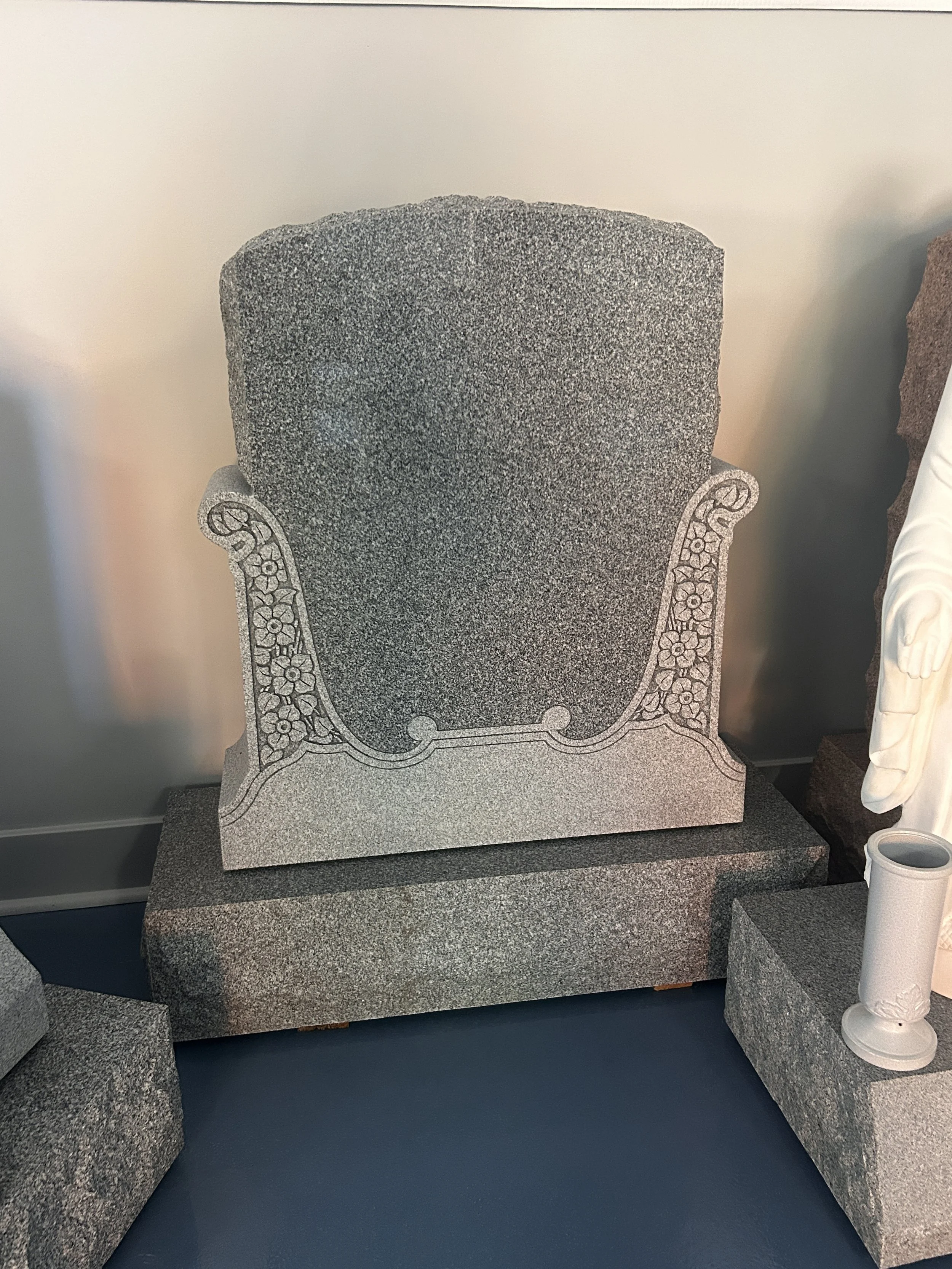 Granite tombstone with ornate carvings on each side, set on a granite base
