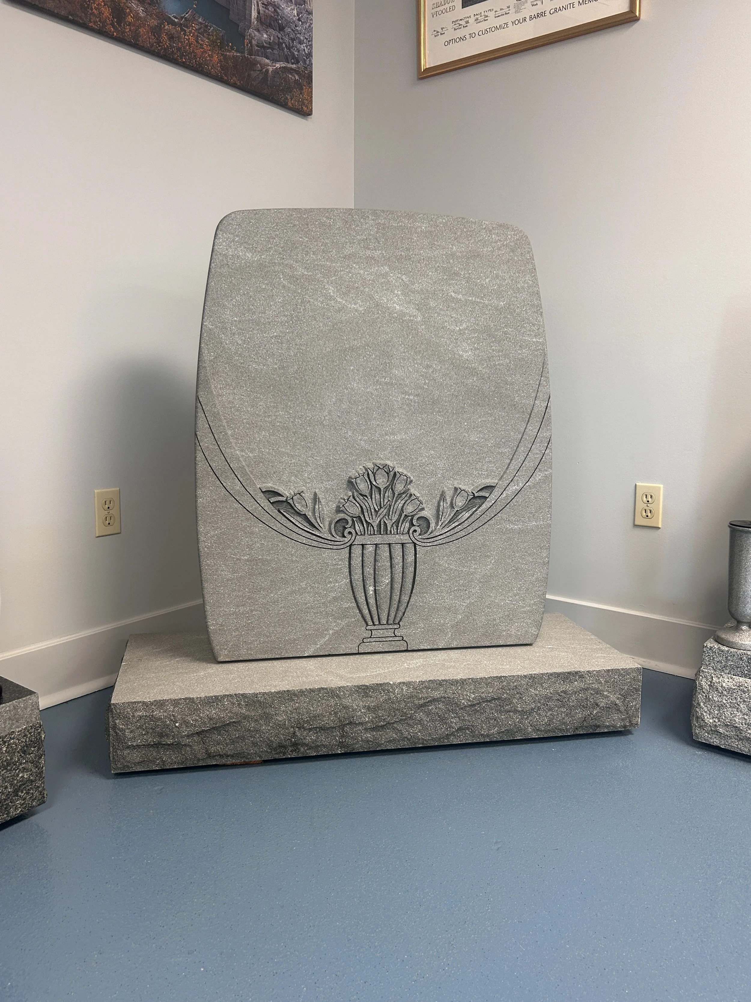 A granite plaque with a decorative urn and floral design engraved on it