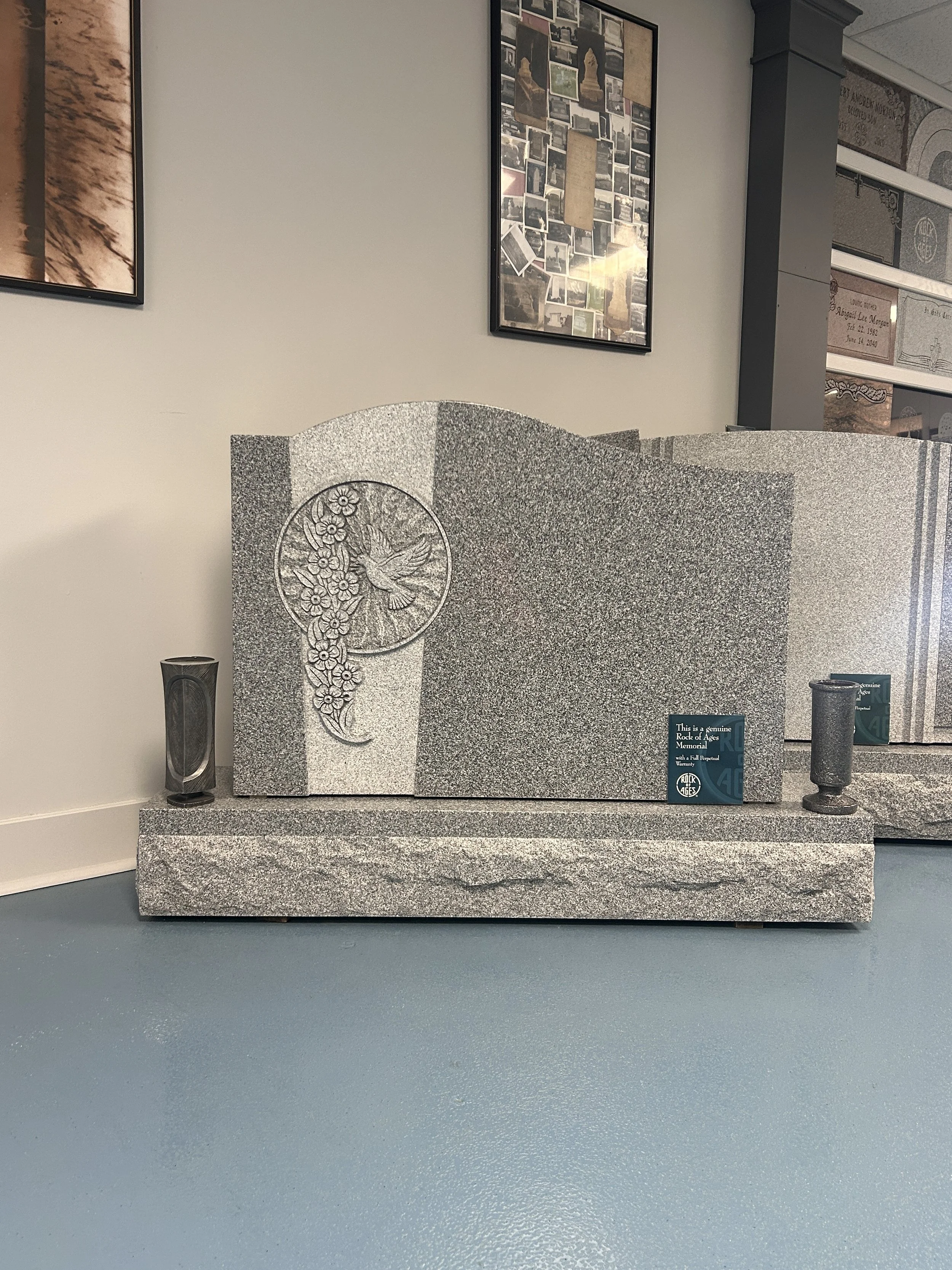 A gray granite memorial with a carved hummingbird and flowers