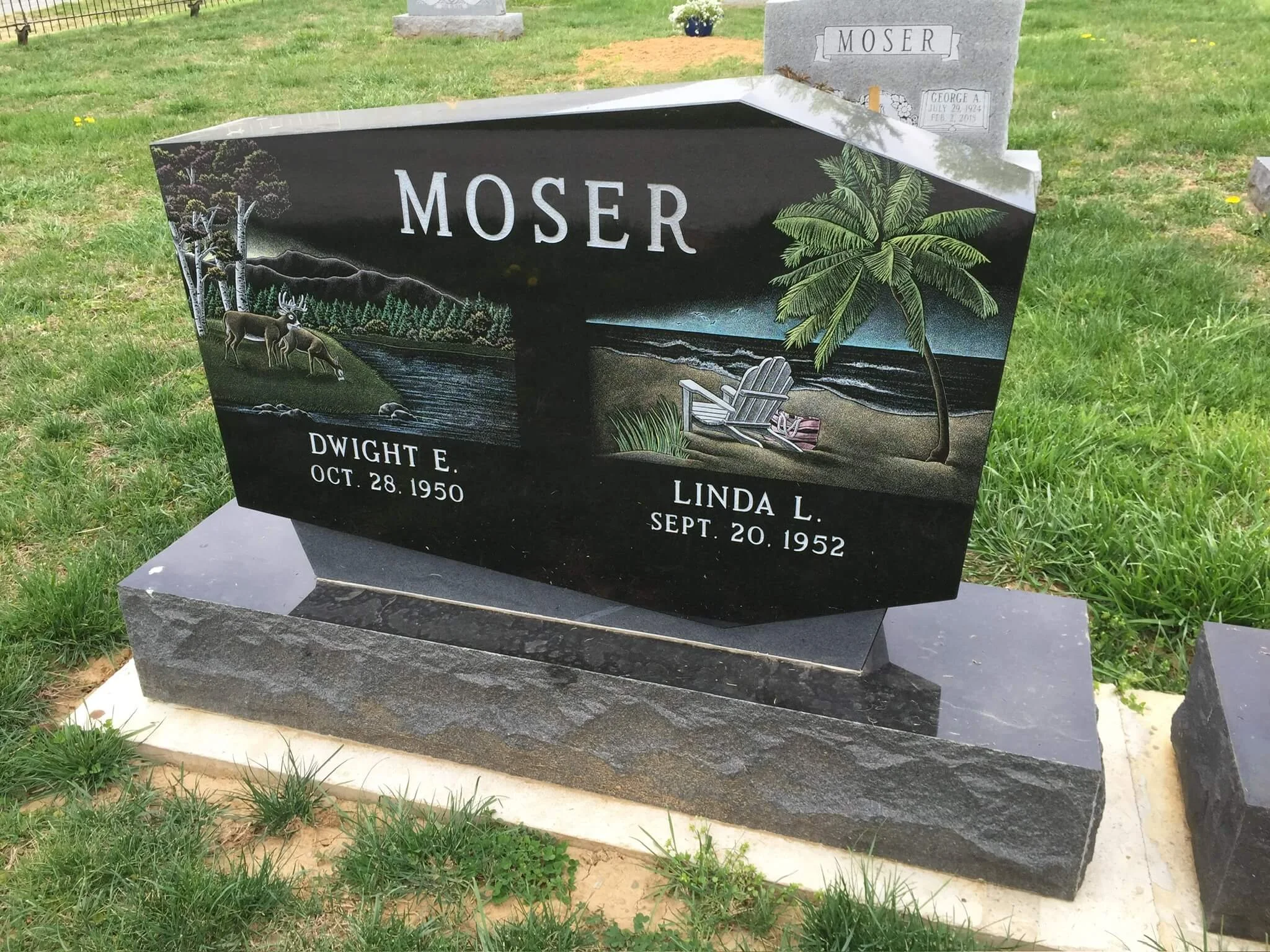 Gravestone with the name Moser, featuring a painted outdoor scene with trees, mountains, a river, a chair on the beach, and a palm tree.