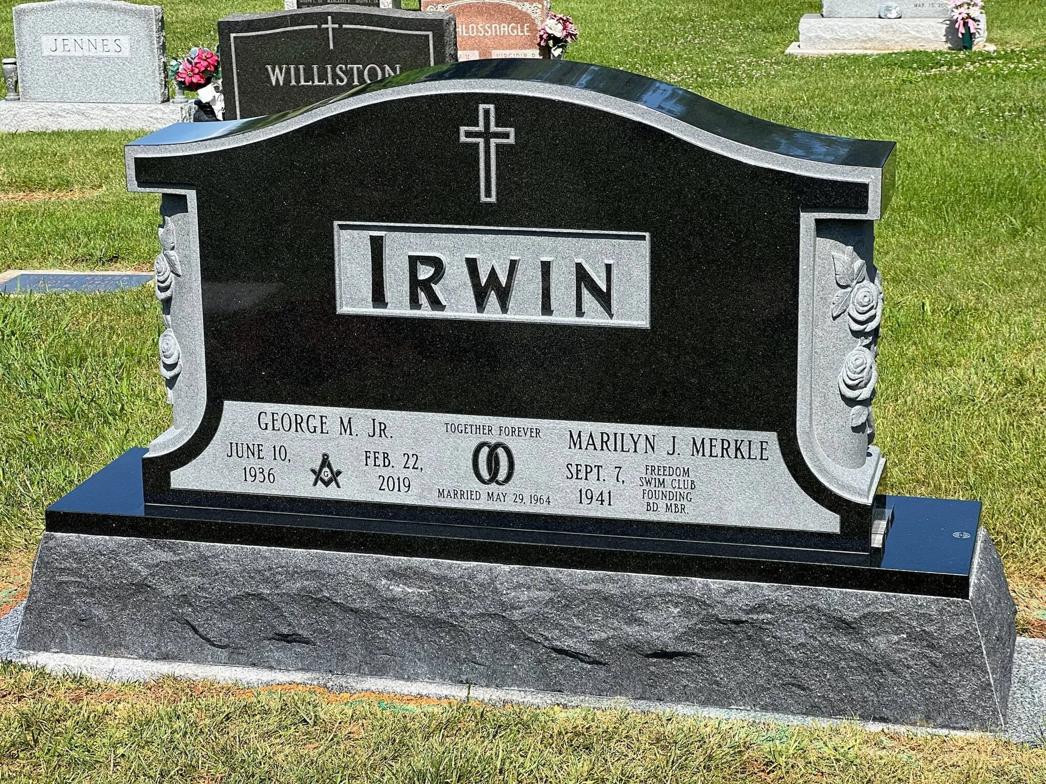 A black and gray granite gravestone with a cross at the top and the initials IRWIN in the center created by Lough Memorials