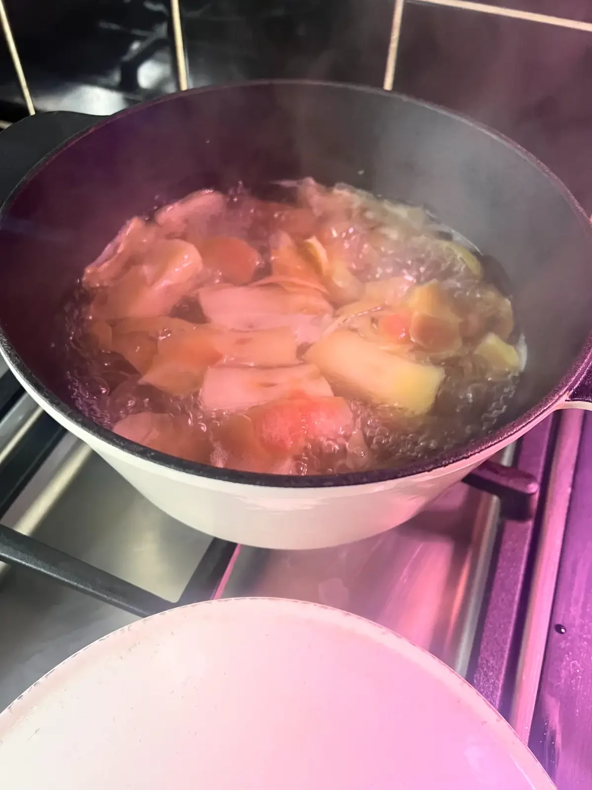 Apple peels and cores simmering in a pan on a stove.