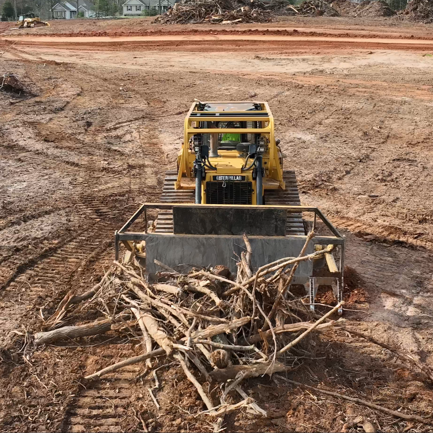 Bulldozer with cage pushing a pile of sticks