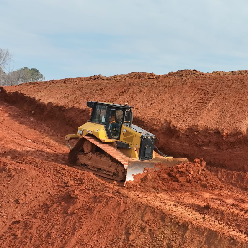 Caterpillar Bulldozer pushing a pile of red dirt on a construction job site.