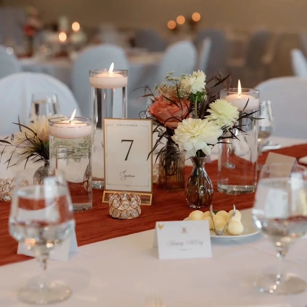 Elegant wedding reception table with candlelit glasses, floral centerpieces, and a table number 7 sign.