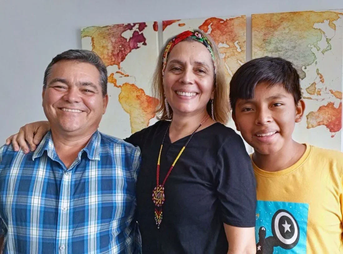Three smiling people standing in front of a world map wall art.