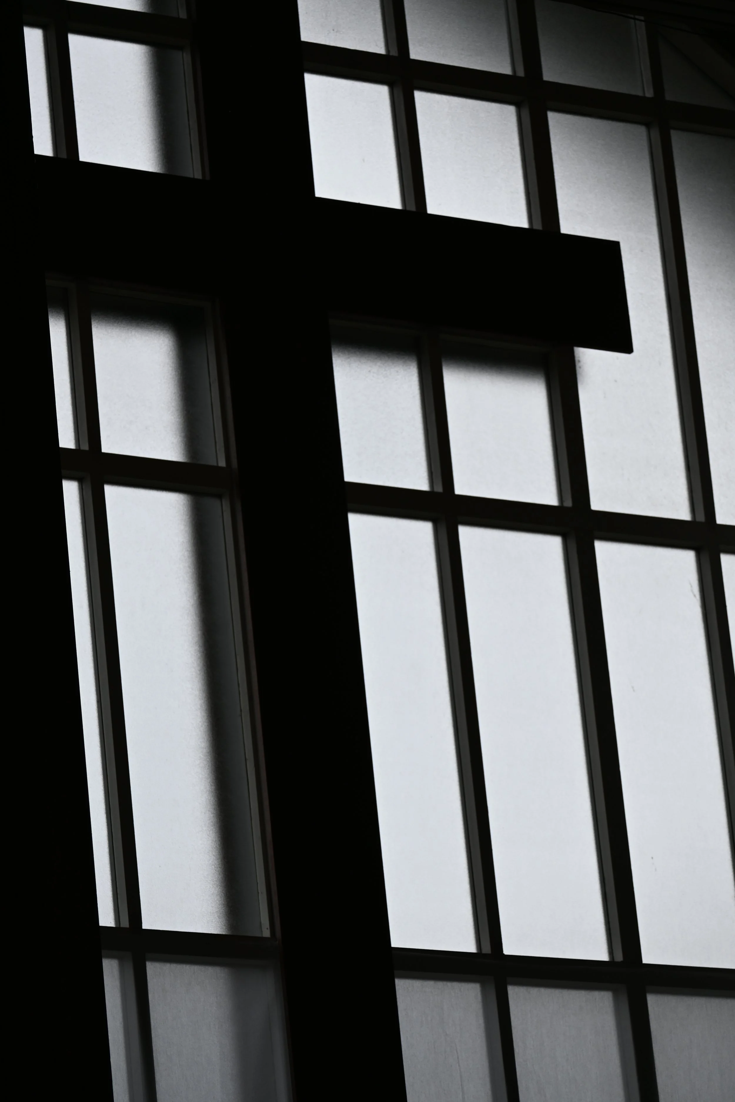 A silhouette of a cross silhouette on a window with frosted glass panes.